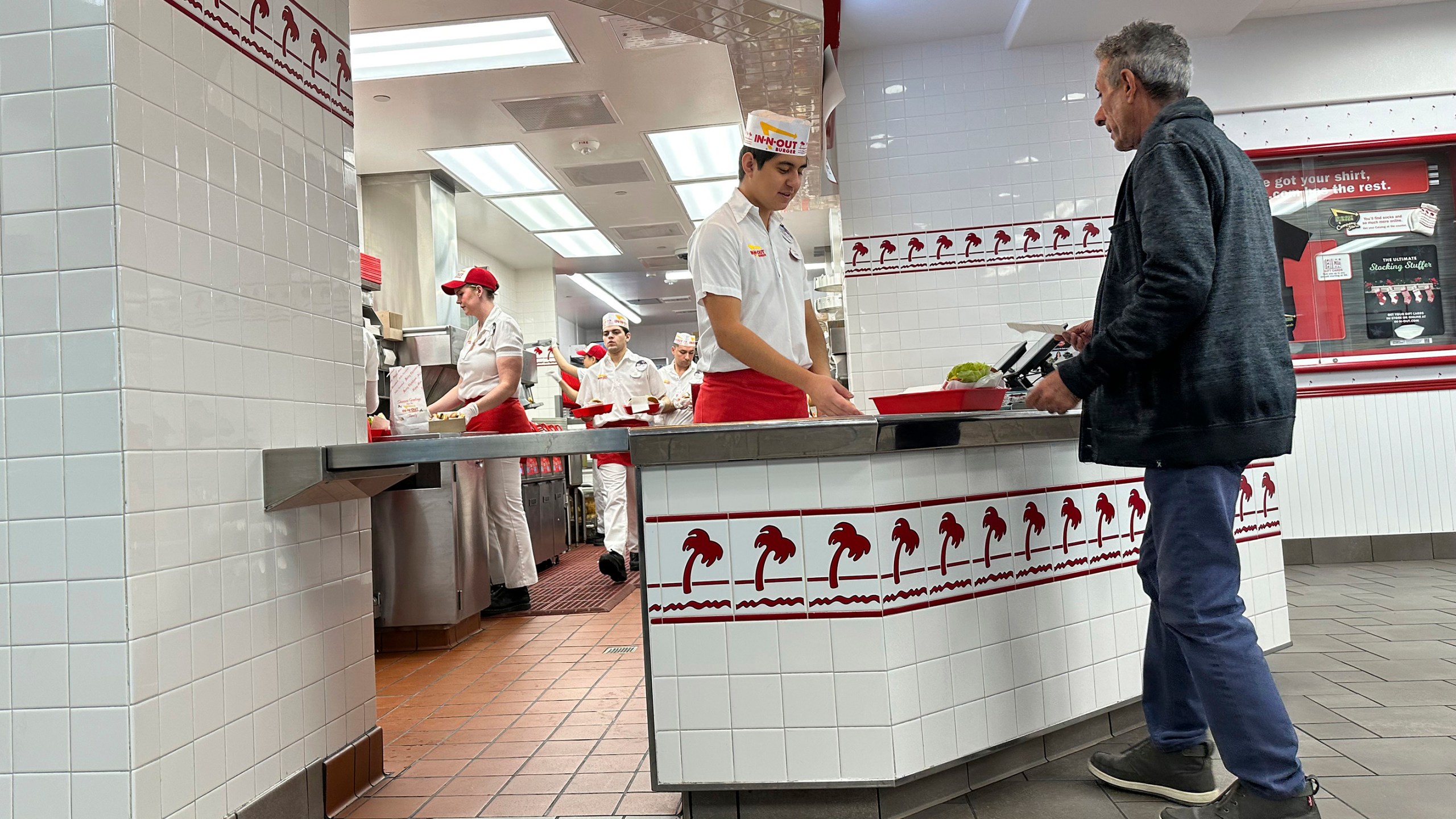 A customer picks up an order at the counter of an In-N-Out Burger restaurant Dec. 8, 2024, in Lone Tree, Colo. (AP Photo/David Zalubowski)