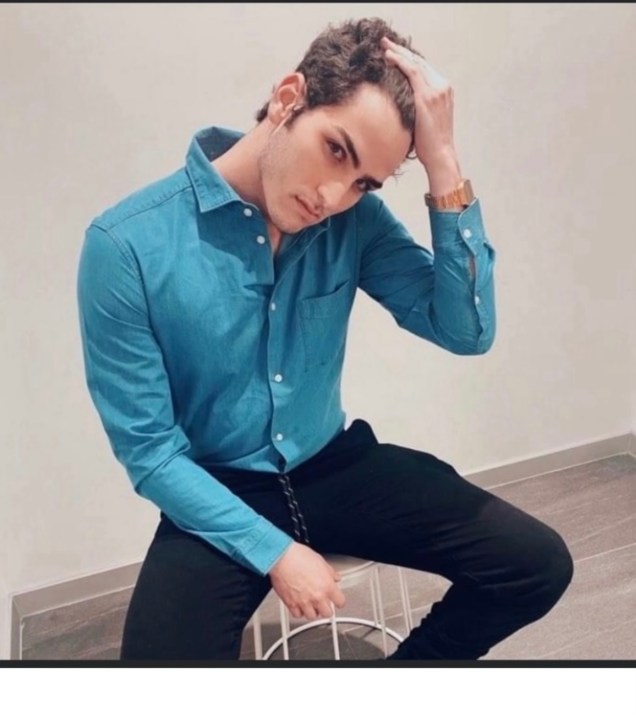 A  young man with his hand in his hair.