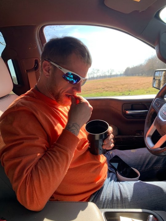 A man in a truck drinking through a straw