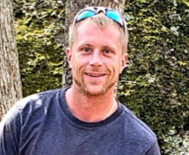 A blond man with sunglasses on his head.