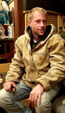 A blond man in a brown coat