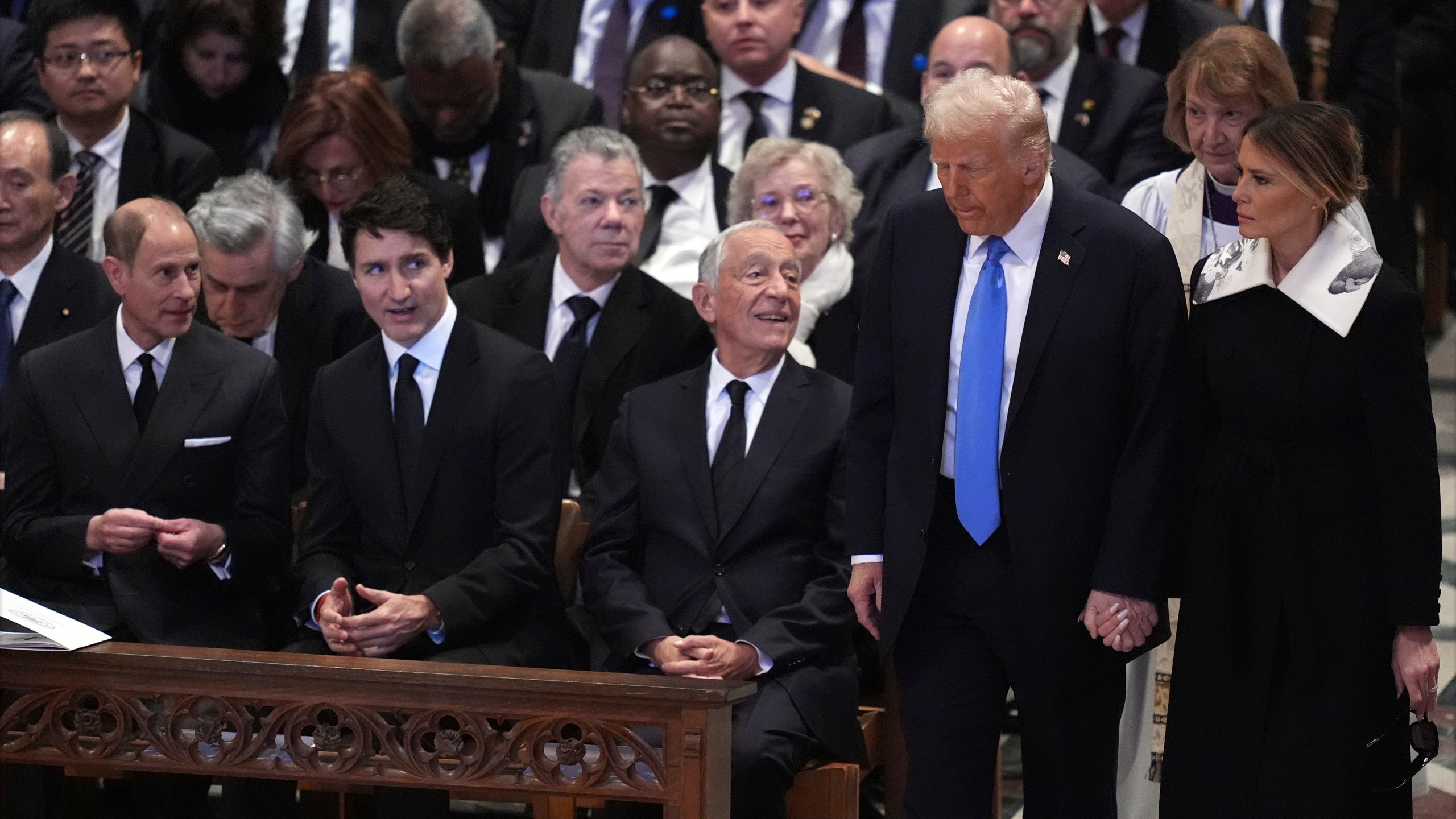 President-elect Donald Trump and Melania Trump arrive before the state funeral for former President Jimmy Carter at Washington National Cathedral in Washington, Thursday, Jan. 9, 2025, as Prince Edward, Duke of Edinburgh, left, and Canada's Prime Minister Justin Trudeau watch. (AP Photo/Jacquelyn Martin)