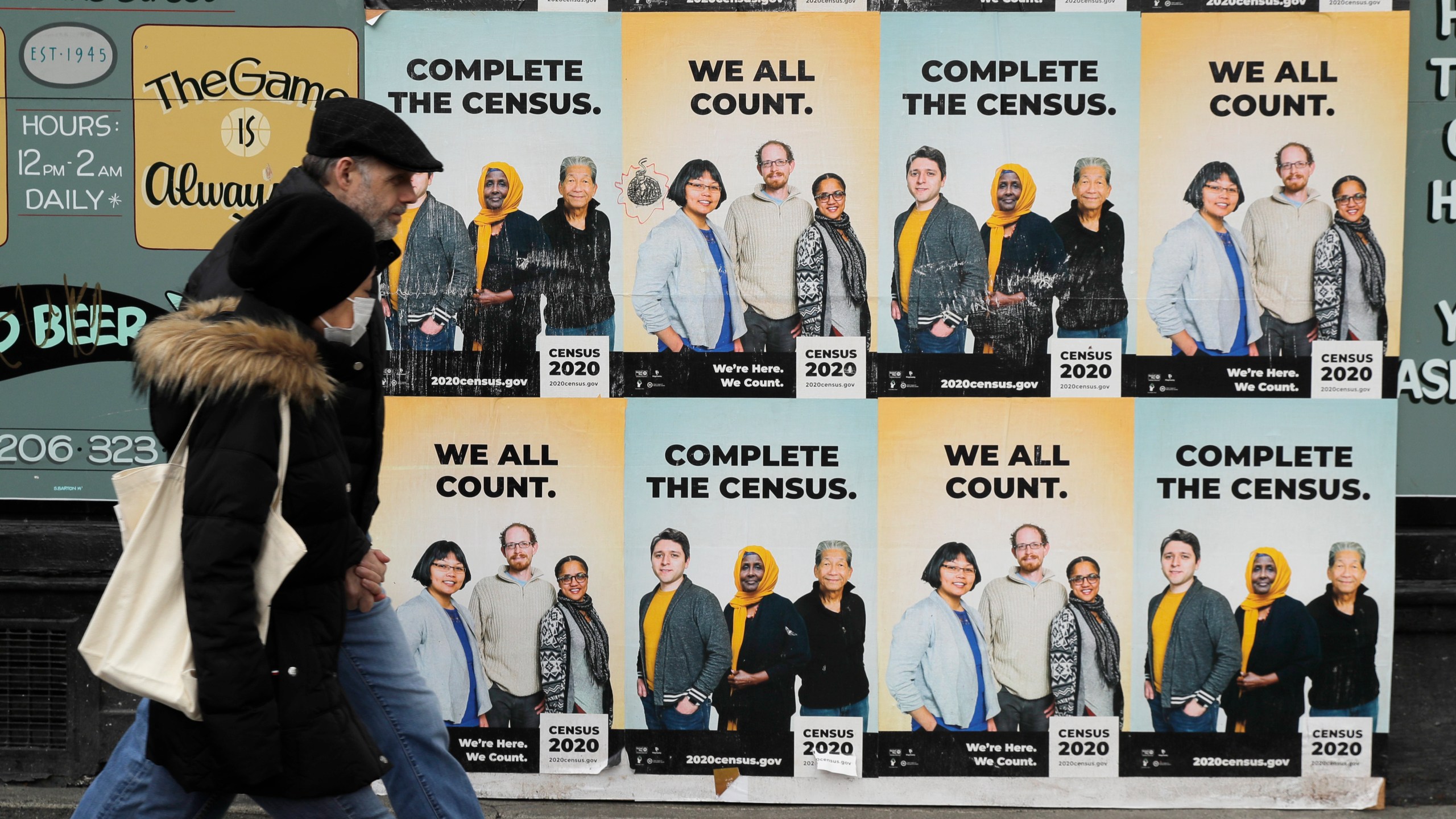 FILE - People walk past posters encouraging participation in the 2020 Census in Seattle's Capitol Hill neighborhood, April 1, 2020.(AP Photo/Ted S. Warren, File)