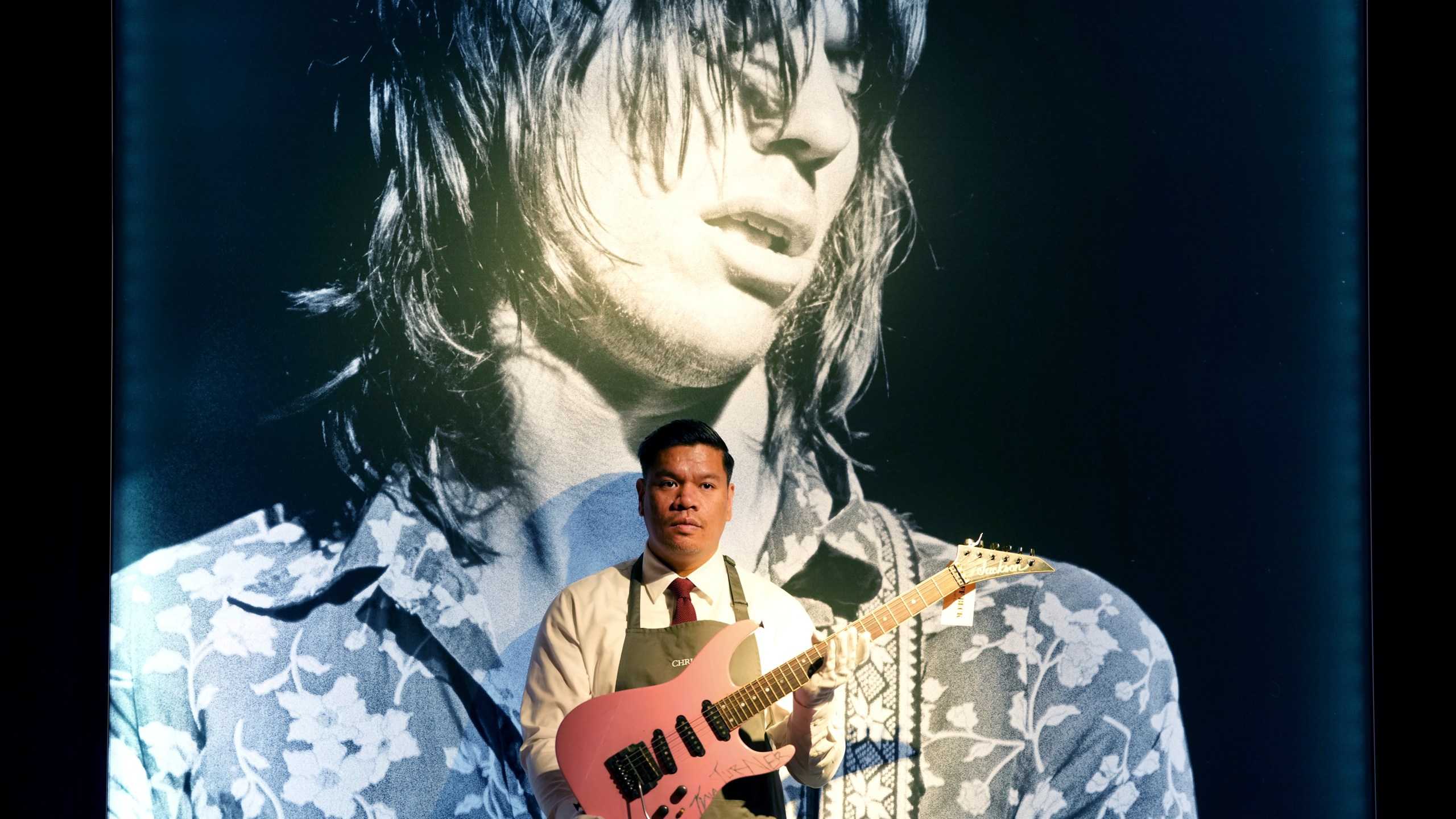 An art handler displays a Jackson, Glendora, California, 1983 a solid-body electric guitar, soloist, signed by Tina Turner, in London, Tuesday, Jan. 14, 2025, ahead of the pre-sale exhibition of Jeff Beck The Guitar Collection at Christie's auction rooms in London. (AP Photo/Kirsty Wigglesworth)