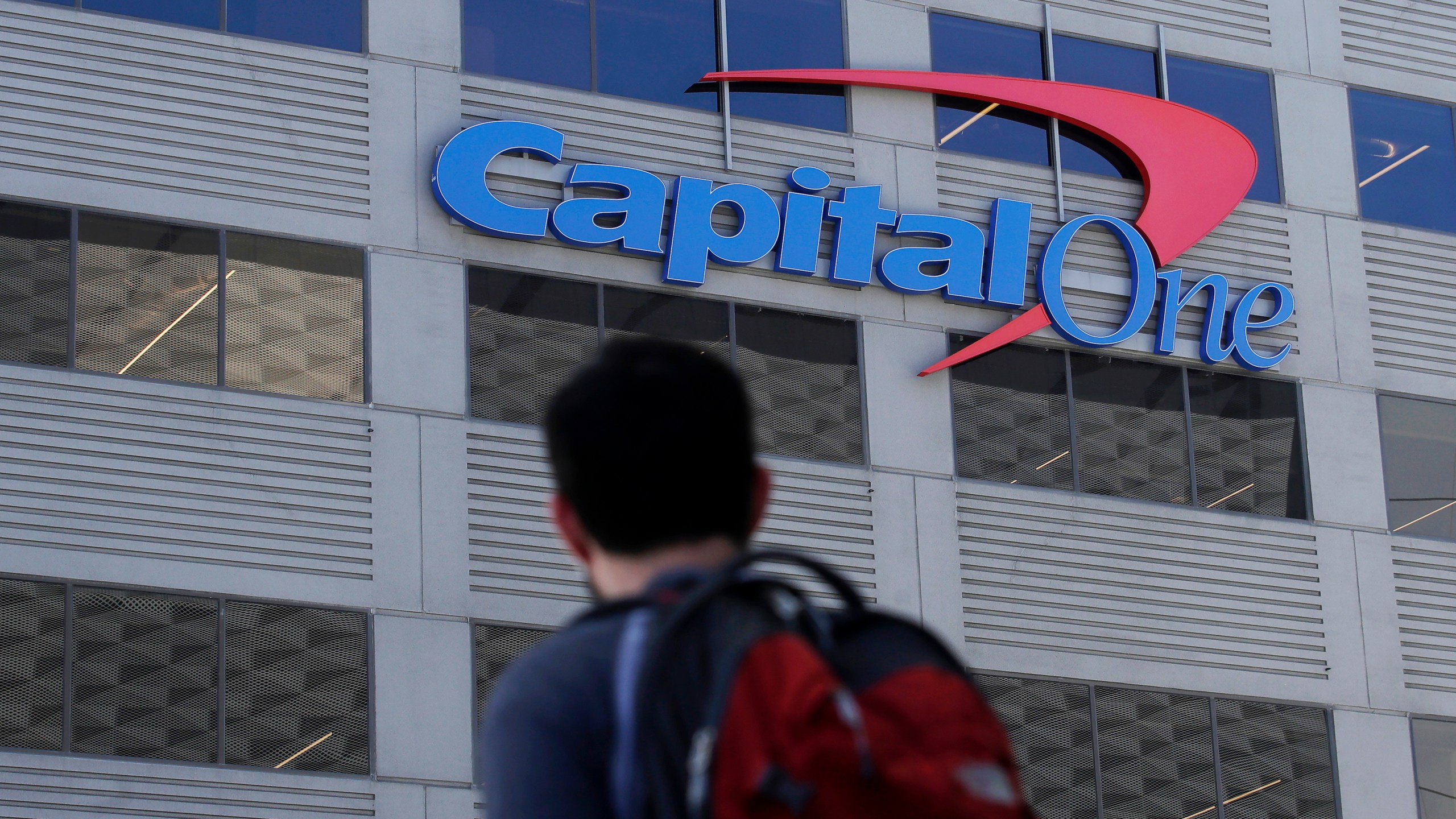 FILE - A man walks across the street from a Capital One location in San Francisco. (AP Photo/Jeff Chiu, File)