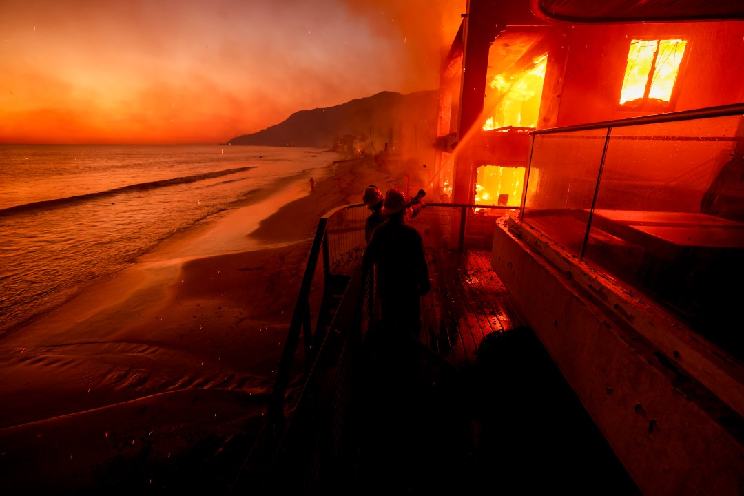 Firefighters work from a deck as the Palisades Fire burns
