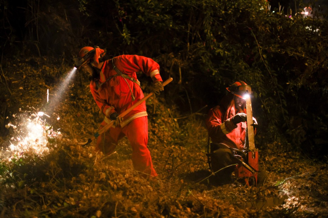 FILE - A California Department of Corrections hand crew works containment lines ahead of the Palisades Fire, Jan. 14, 2025, in Santa Monica, Calif. (AP Photo/Ethan Swope, File)