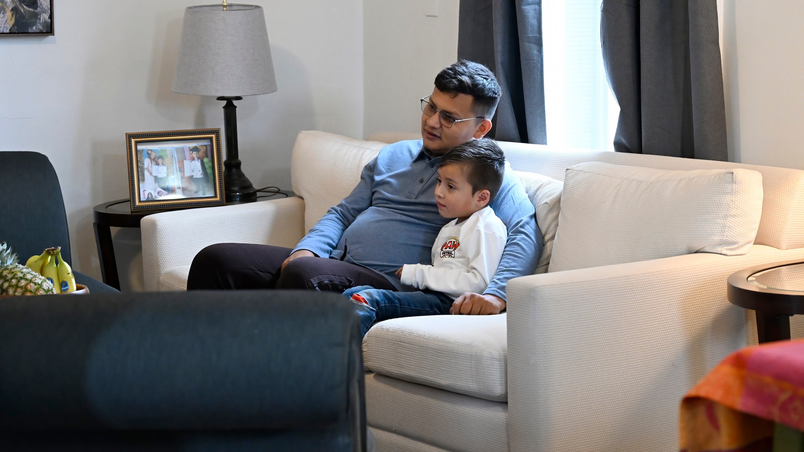 In this Jan. 3, 2025 photo, Rogers Lopez watches television with his son Jesus Lopez in their apartment in New Milford, Conn. (AP Photo/Jessica Hill)