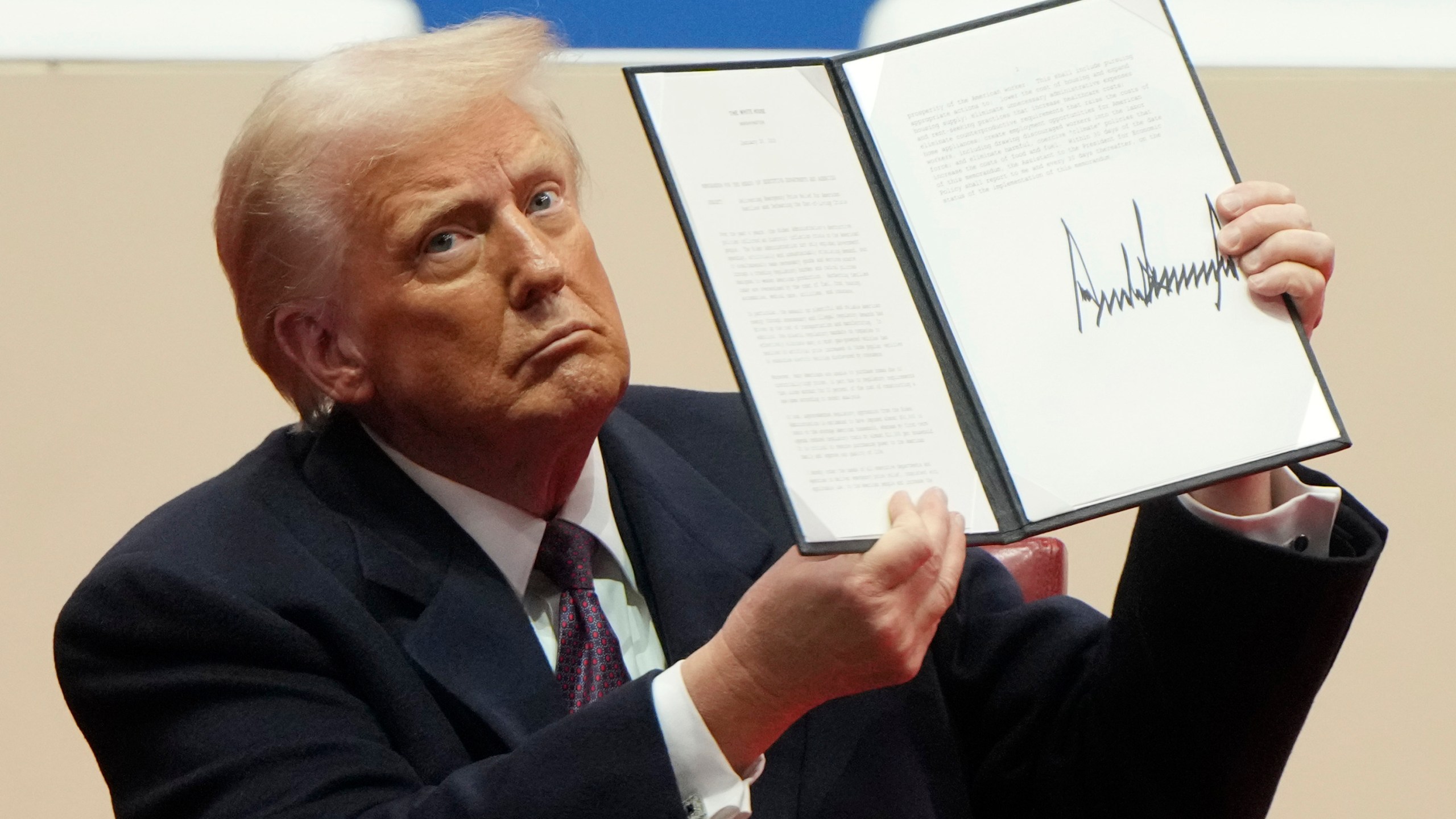 President Donald Trump holds up an executive order after signing it at an indoor Presidential Inauguration parade event in Washington, Monday, Jan. 20, 2025. (AP Photo/Matt Rourke)