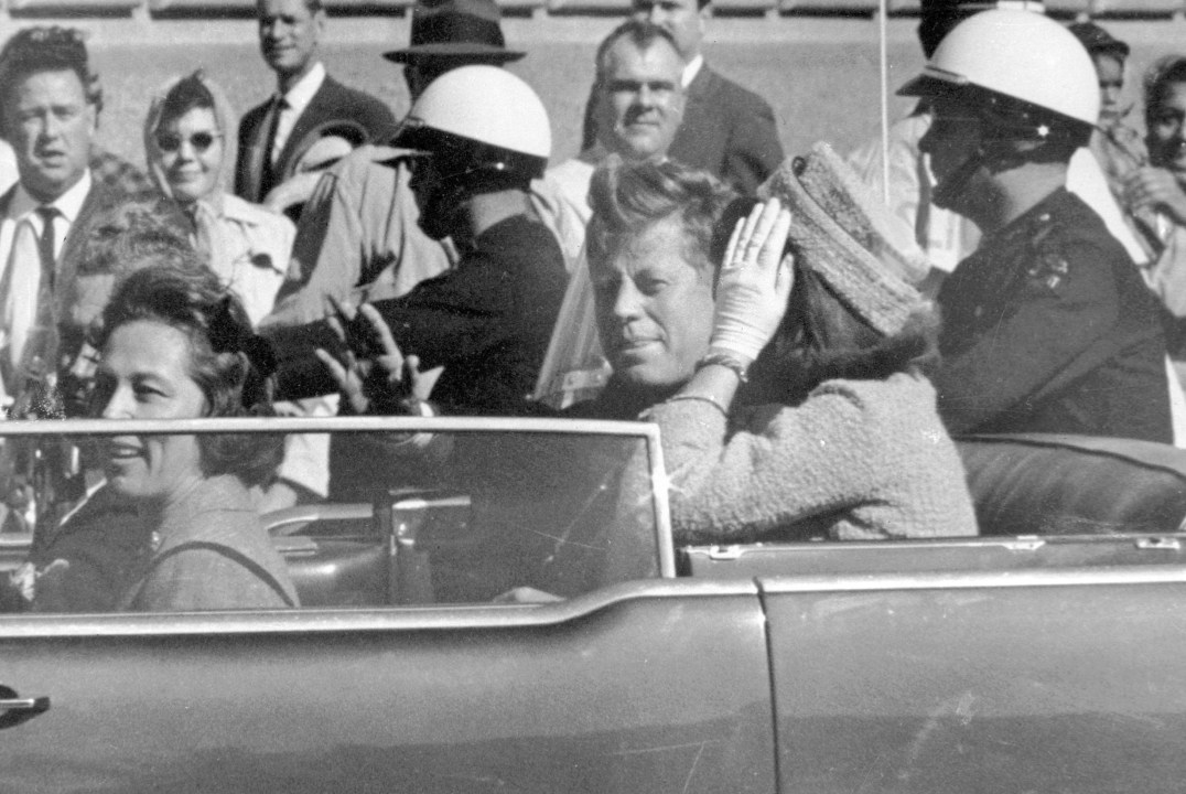 President John F. Kennedy waves from his car in a motorcade in Dallas.