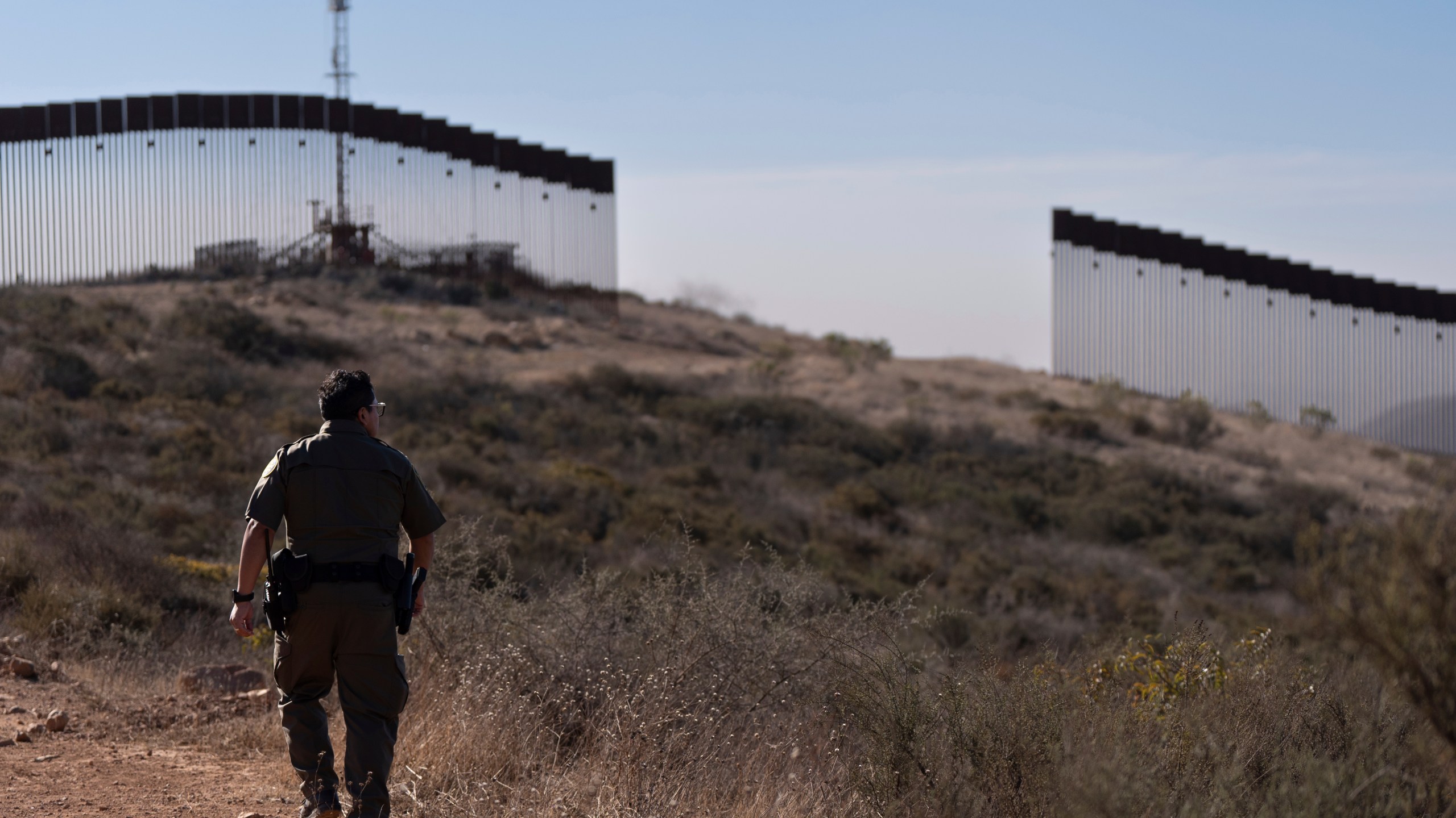 A Border Patrol agent walks towards a gap in one of two border walls separating Mexico from the United States, Thursday, Jan. 23, 2025, in San Diego. (AP Photo/Gregory Bull)