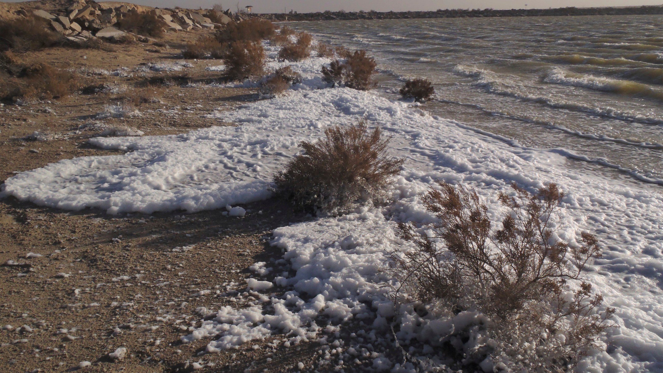 This March 13, 2019, image provided by the New Mexico Environment Department shows foam along the shoreline of Holloman Lake near Alamogordo, N.M. (James Kenney/New Mexico Environment Department via AP)