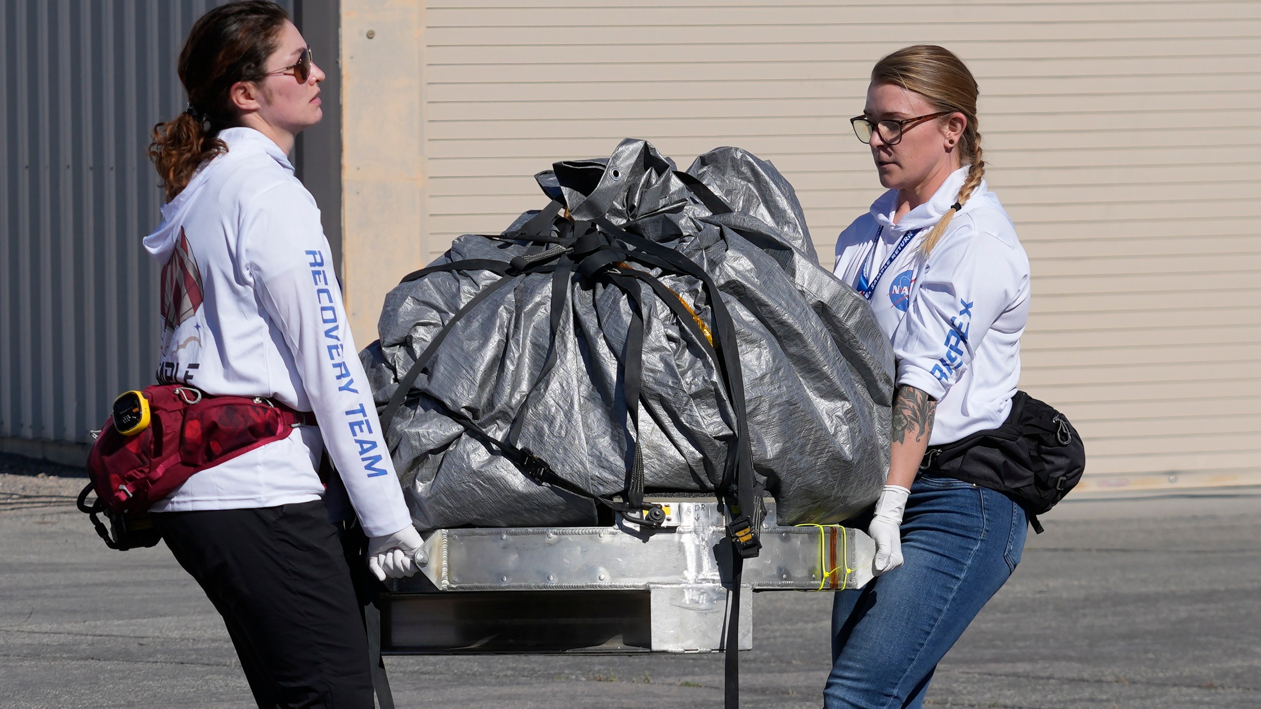 FILE - Recovery team members carry a capsule containing NASA's first asteroid samples to a temporary clean room at Dugway Proving Ground in Utah on Sept. 24, 2023. (AP Photo/Rick Bowmer, Pool, file)