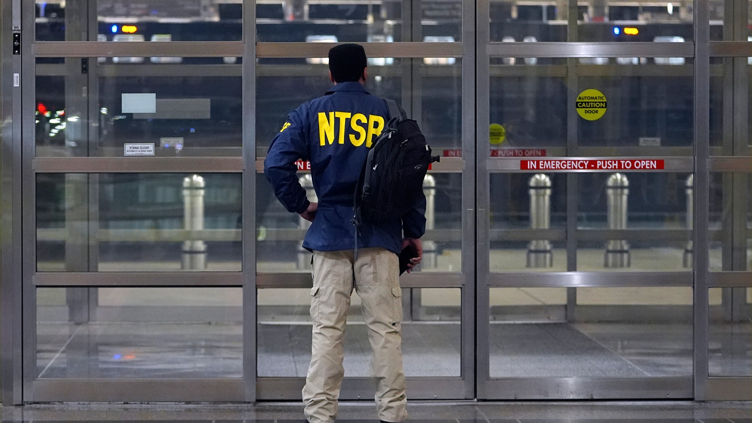 A member of the National Transportation Safety Board (NTSB) stands by a door at Ronald Reagan Washington National Airport, Wednesday, Jan. 29, 2025, in Arlington, Va. (AP Photo/Julio Cortez)