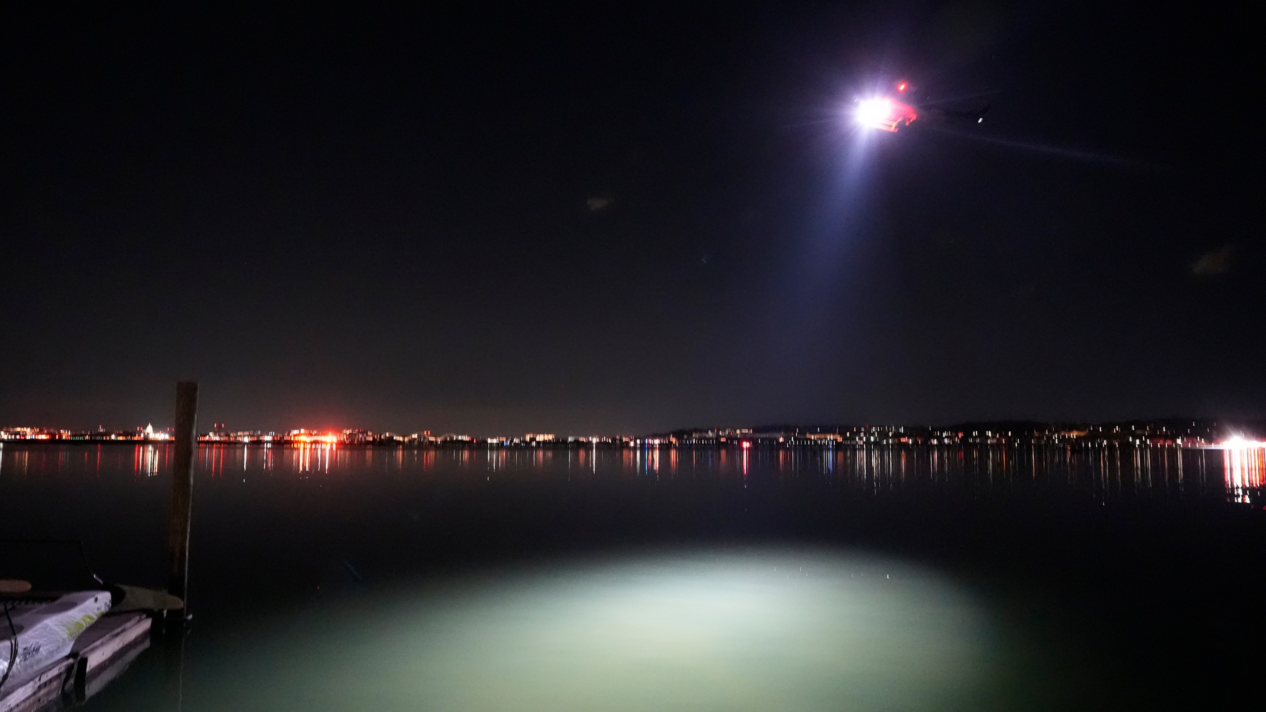 A helicopter uses a spotlight on the Potomac River near Ronald Reagan Washington National Airport, Thursday, Jan. 30, 2025, in Arlington, Va. (AP Photo/Alex Brandon)