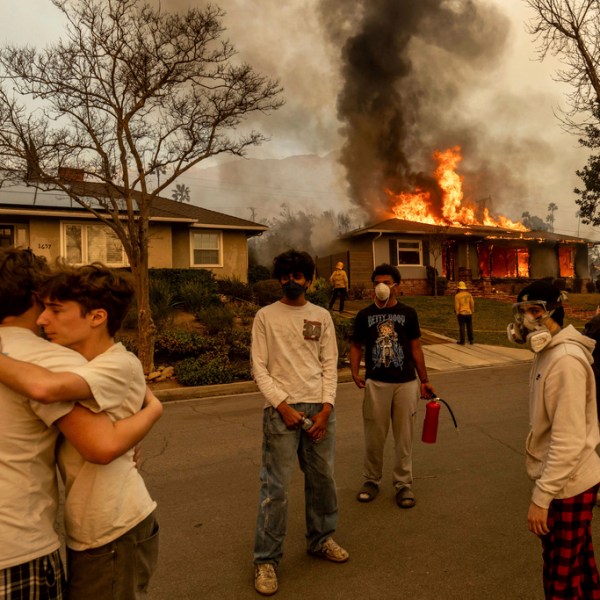 People embracing outside a burning property