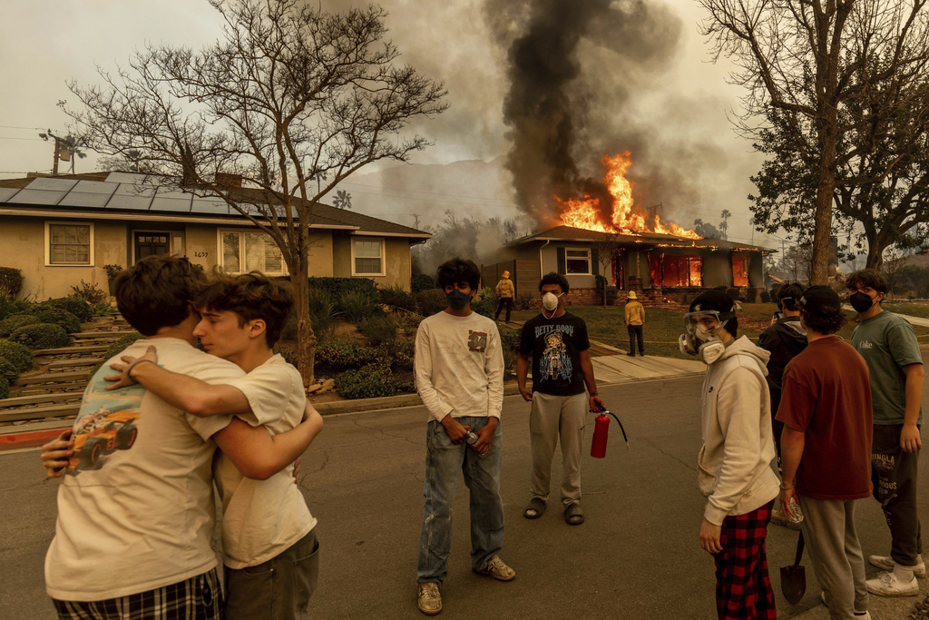 People embracing outside a burning property