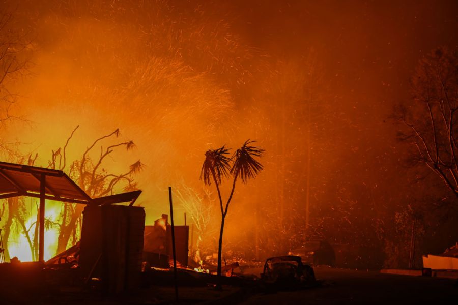 A house in on fire as residents try to escape the site in Pacific Palisades, Calif.