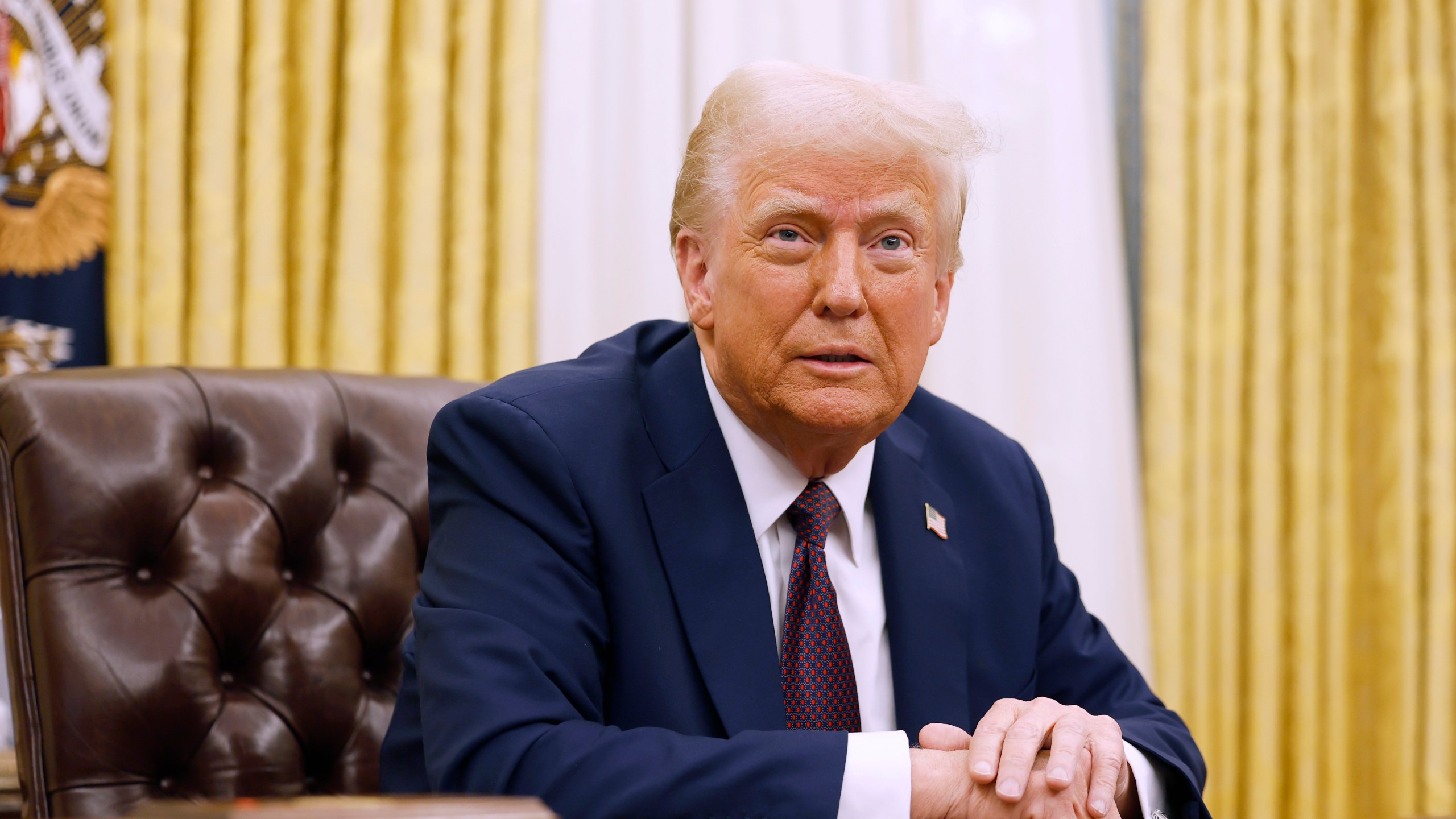 Donald Trump sits at his desk in the Oval Office