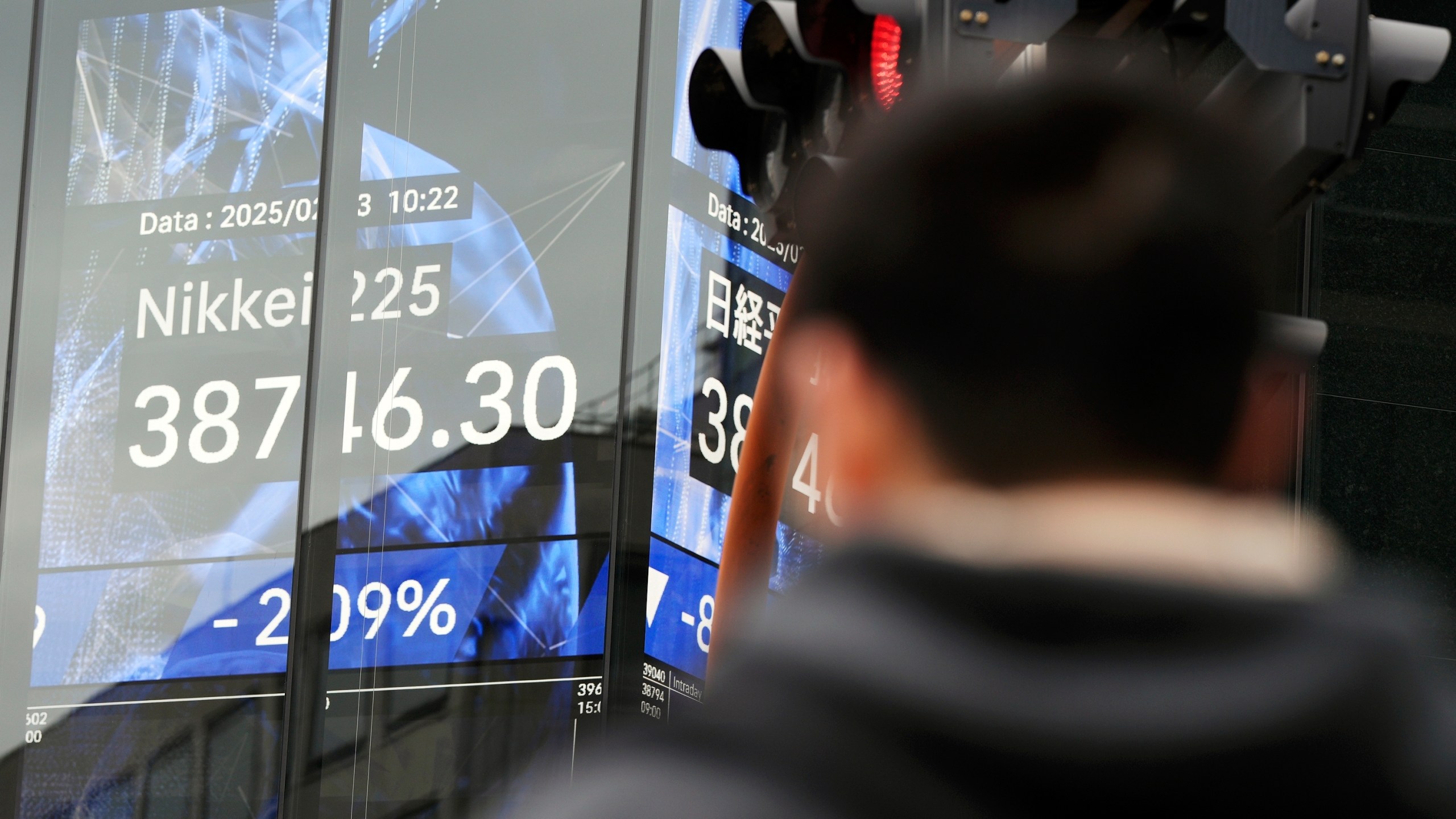 A person walks in front of an electronic stock board showing Japan's Nikkei index at a securities firm Monday, Feb. 3, 2025, in Tokyo. (AP Photo/Eugene Hoshiko)