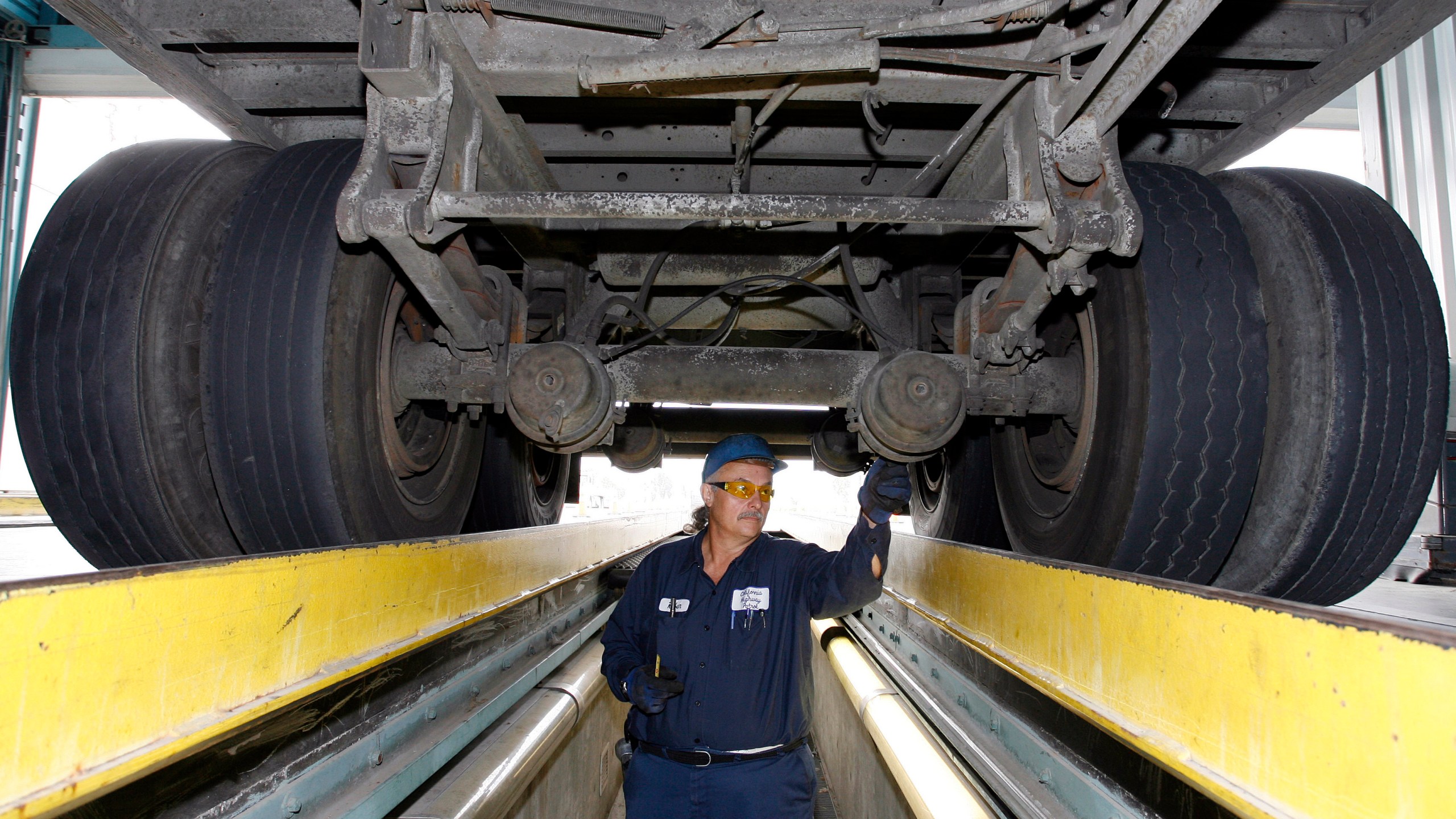 FILE - California Highway Patrol commercial vehicle inspector Ruben Montanez inspects the undercarriage of a truck entering the U.S. from Mexico at the CHP's Otay Mesa Inspection Station Thursday, Sept. 6, 2007, in San Diego. (AP Photo/Denis Poroy)