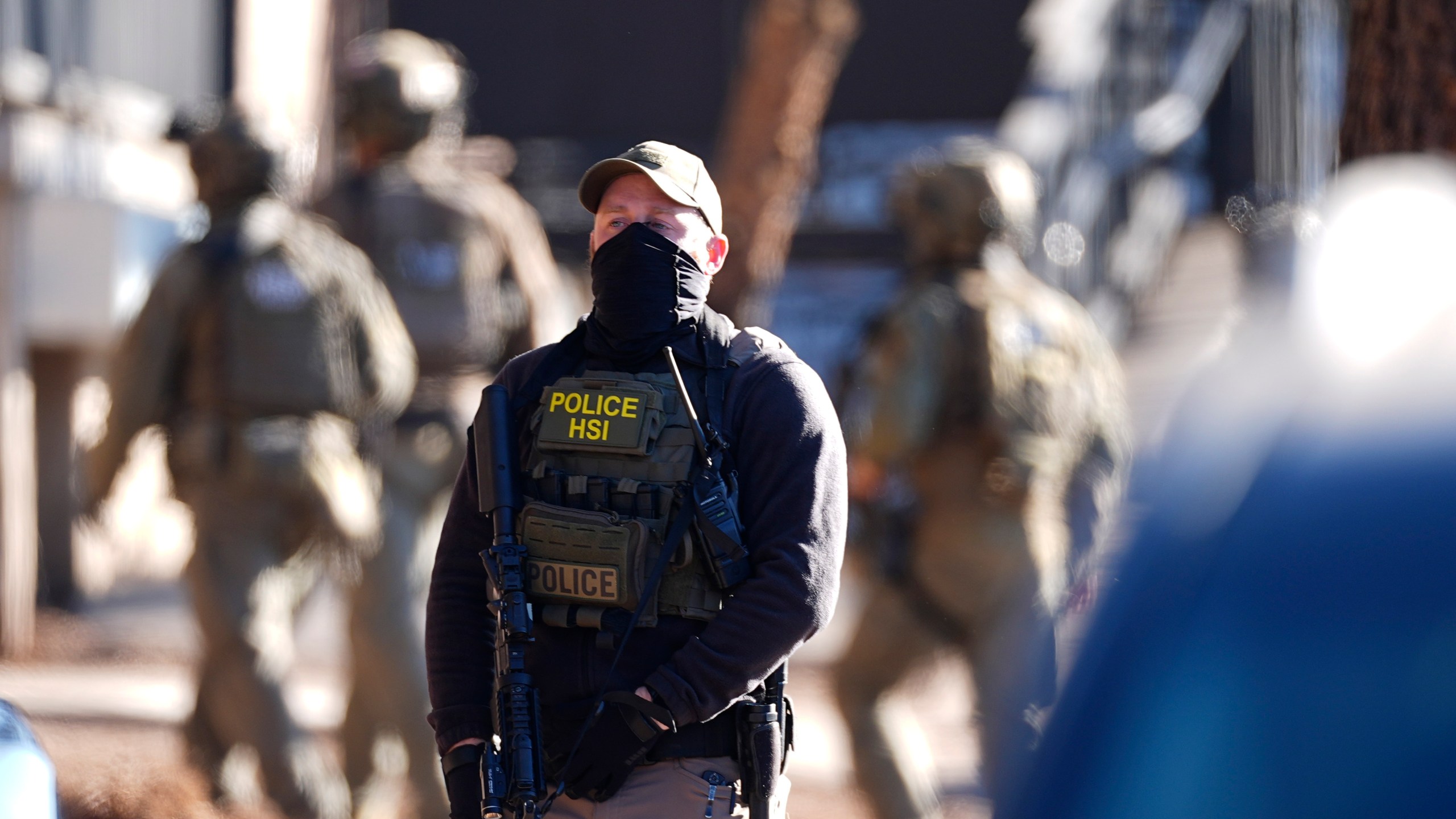 Law officials move through an apartment complex during a raid Wednesday, Feb. 5, 2025, in east Denver. (AP Photo/David Zalubowski)