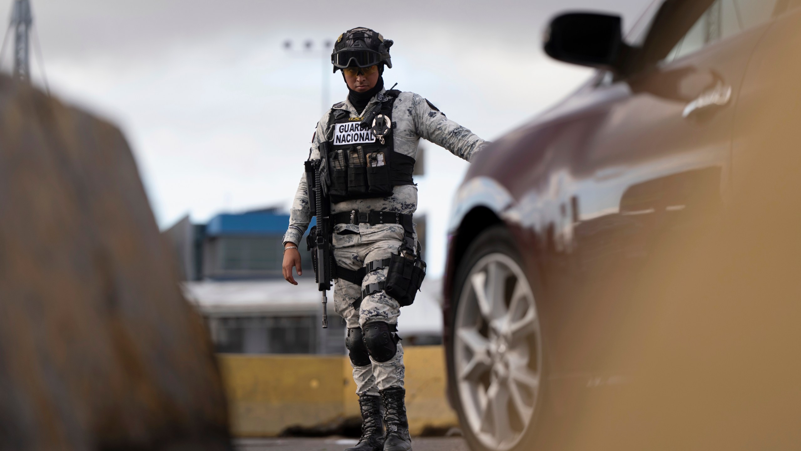Members of Mexico's National Guard stand guard at an inspection checkpoint for cars in line to cross the border into the United States from Mexico at the San Ysidro Port of Entry, Thursday, Feb. 6, 2025, in Tijuana, Mexico. (AP Photo/Gregory Bull)