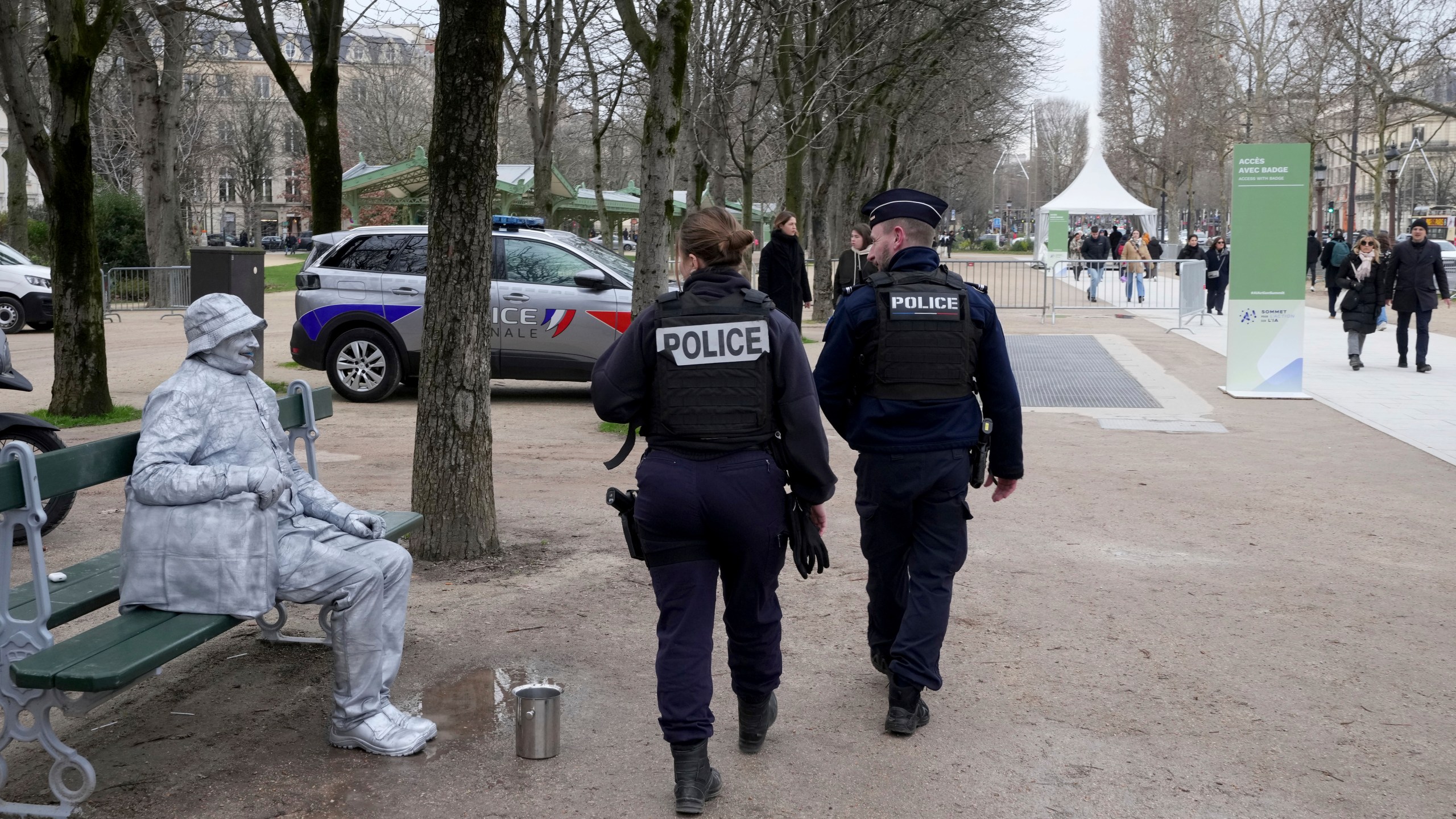 Police walk by a street performer outside of the Grand Palais, which will be the venue for an upcoming AI Action Summit, in Paris, Sunday, Feb. 9, 2025. (AP Photo/Michel Euler)