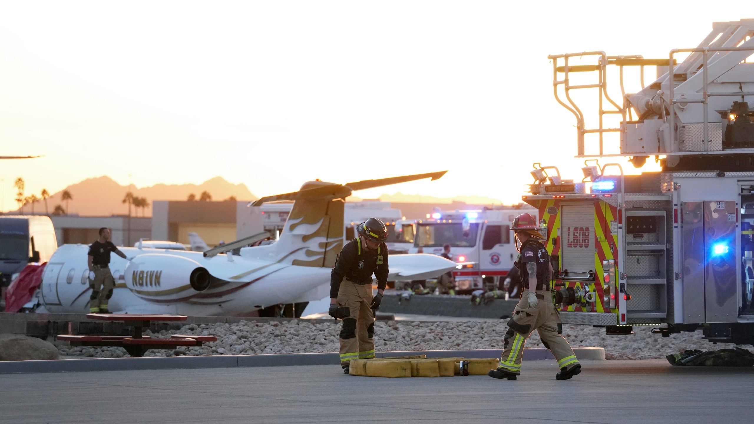 Firefighters work around the site of a crashed Learjet at Scottsdale Airport after it collided with a parked plane Monday, Feb. 10, 2025, in Scottsdale, Ariz. (AP Photo/Ross D. Franklin)