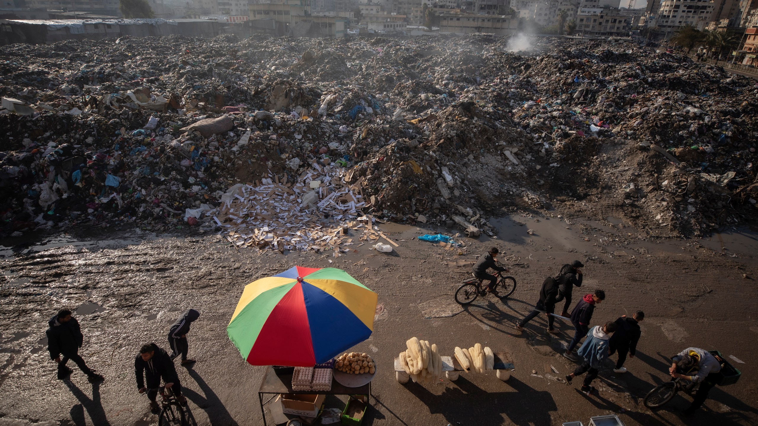 Palestinians walk past a pile of burning garbage, as there is no refuse collection in the city and people are disposing of their rubbish in the streets, in Gaza City, Wednesday, Feb. 12, 2025. (AP Photo/Jehad Alshrafi)