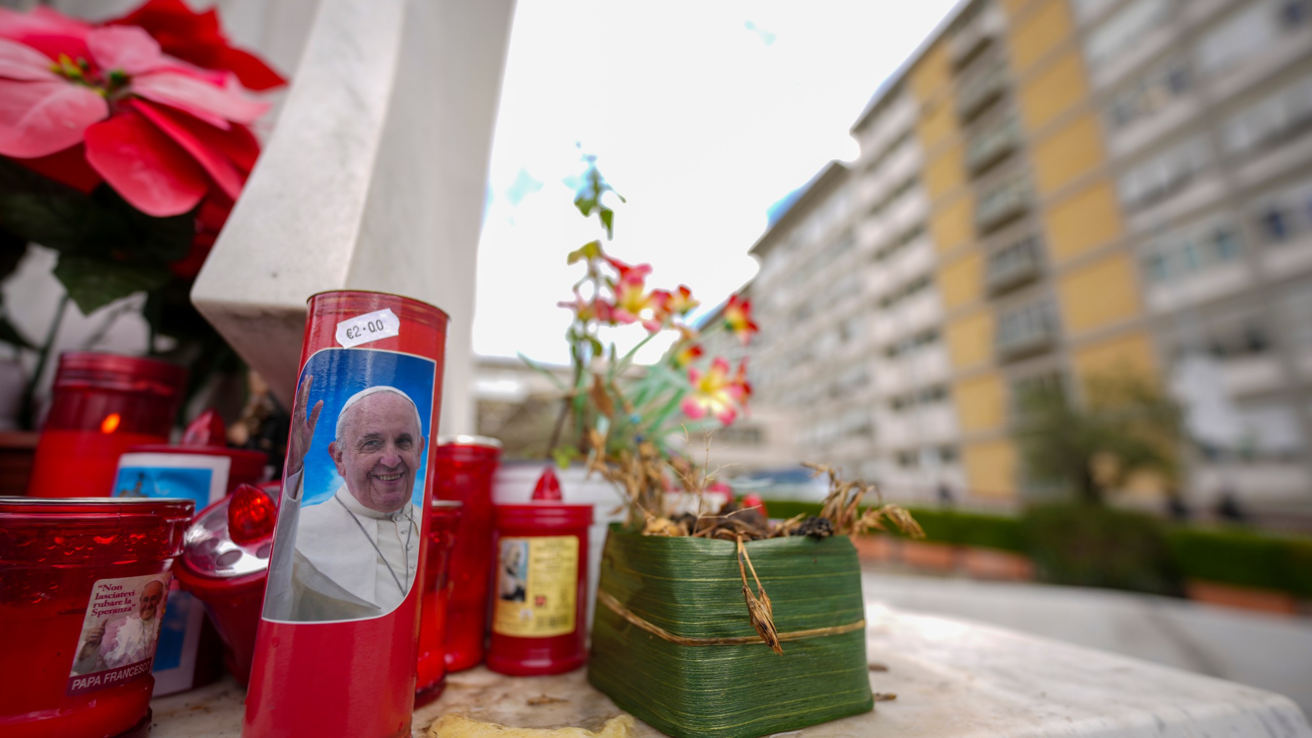 Candles, one showing a photo of Pope Francis, are seen in front of the Agostino Gemelli Polyclinic in Rome, Friday, Feb. 14, 2025, where Pope Francis has been hospitalized to undergo some necessary diagnostic tests and to continue his ongoing treatment for bronchitis. (AP Photo/Andrew Medichini)
