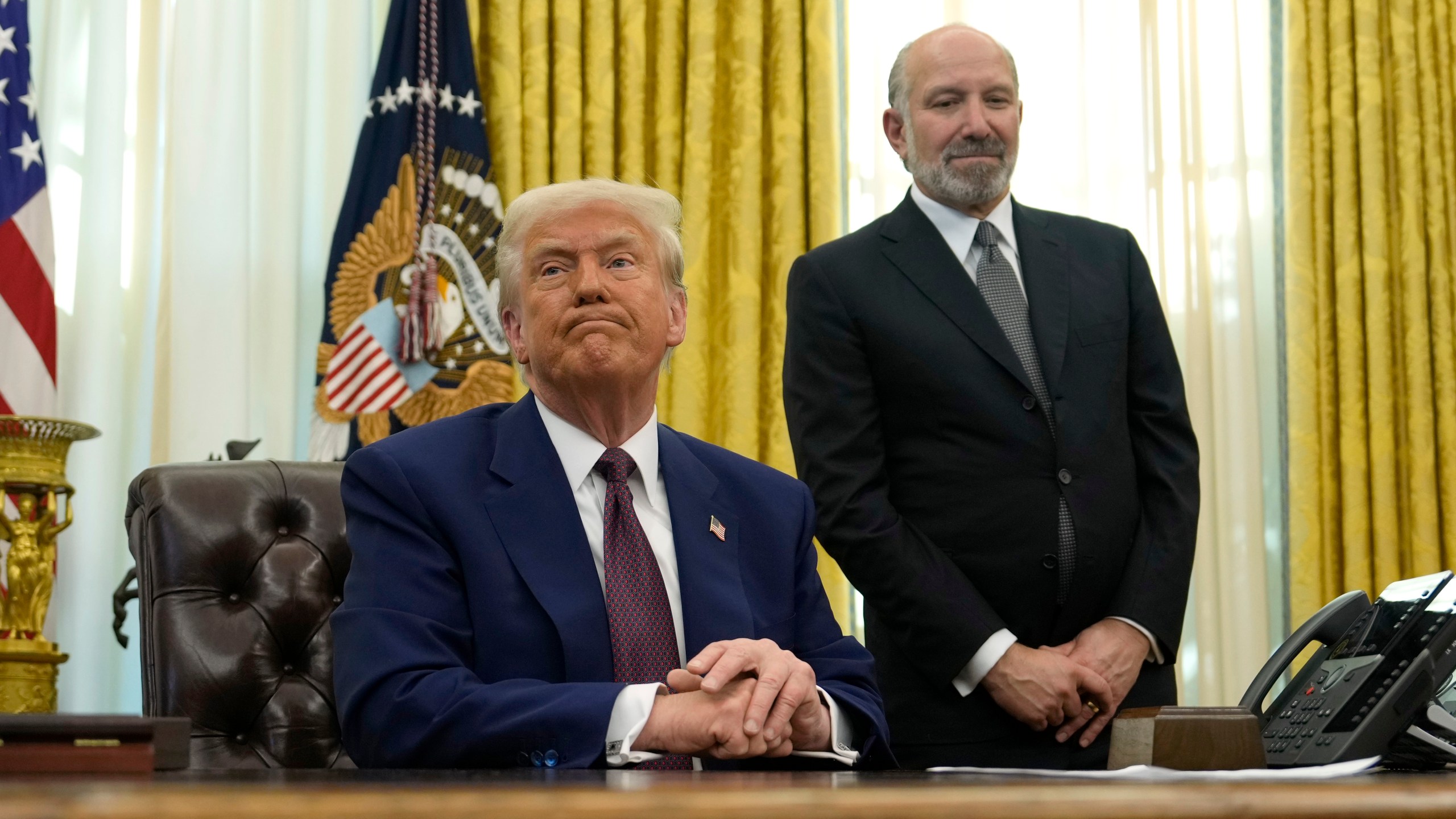 President Donald Trump listens from his desk in the Oval Office