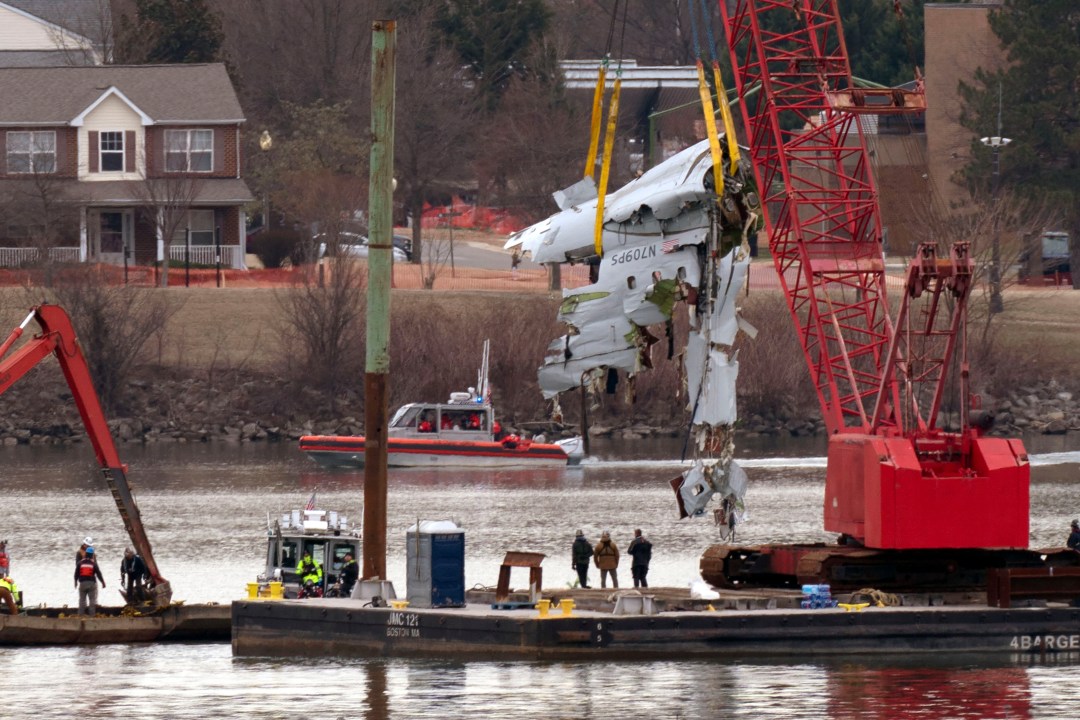 Cranes pulling up the wreckage of an American Airlines jet from a river