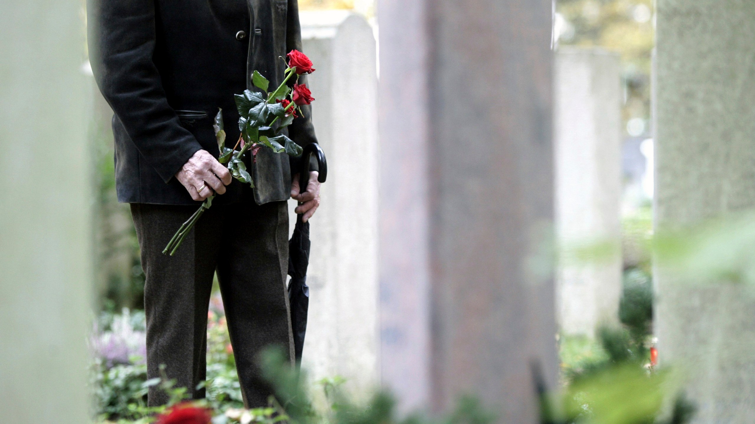 FILE - A man stands in front of gravestones at the Waldfriedhof cemetery in Munich, Germany, Wednesday, Nov. 1, 2006. (AP Photo/Christof Stache, File)