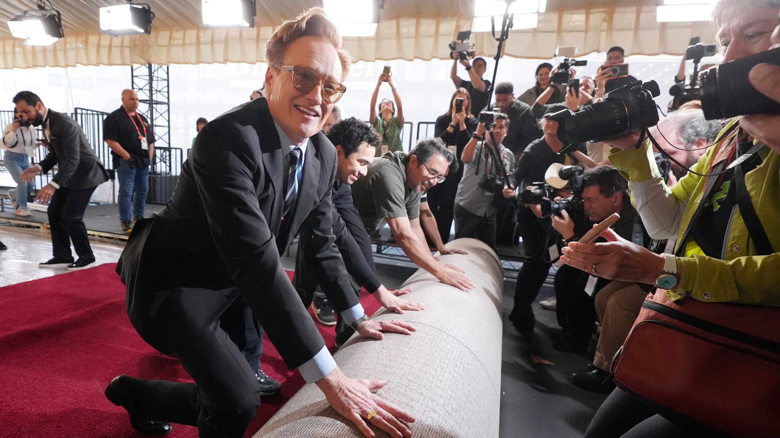 Conan O'Brien, host of Sunday's 97th Academy Awards, helps to roll out the red carpet for the show at the Dolby Theatre on Wednesday, Feb. 26, 2025, in Los Angeles. (AP Photo/Chris Pizzello)