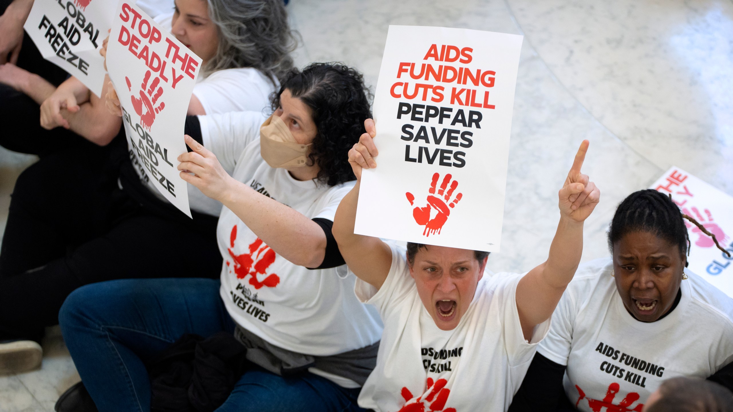 Demonstrators protest against cuts to American foreign aid spending, including USAID and the PEPFAR program to combat HIV/AIDS, at the Cannon House Office Building on Capitol Hill, Wednesday, Feb. 26, 2025, in Washington. (AP Photo/Mark Schiefelbein)