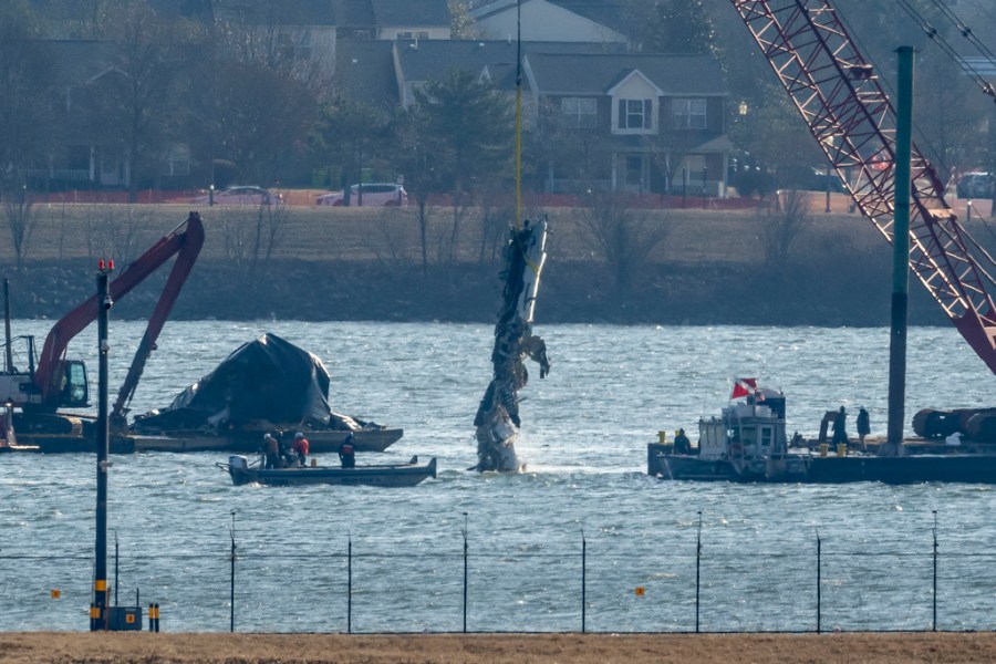 A piece of plane wreckage is lifted from a river
