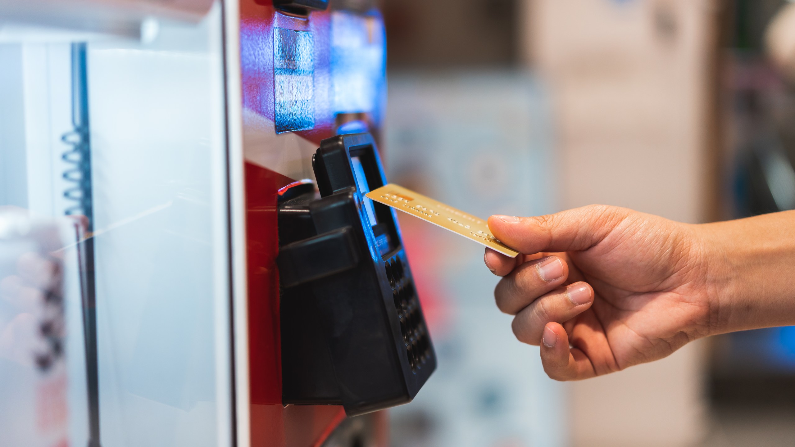 Closeup hand holding credit card to pay at a vending machine