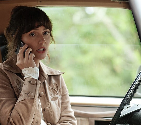 A woman sits in a vehicle and talks on her cell phone
