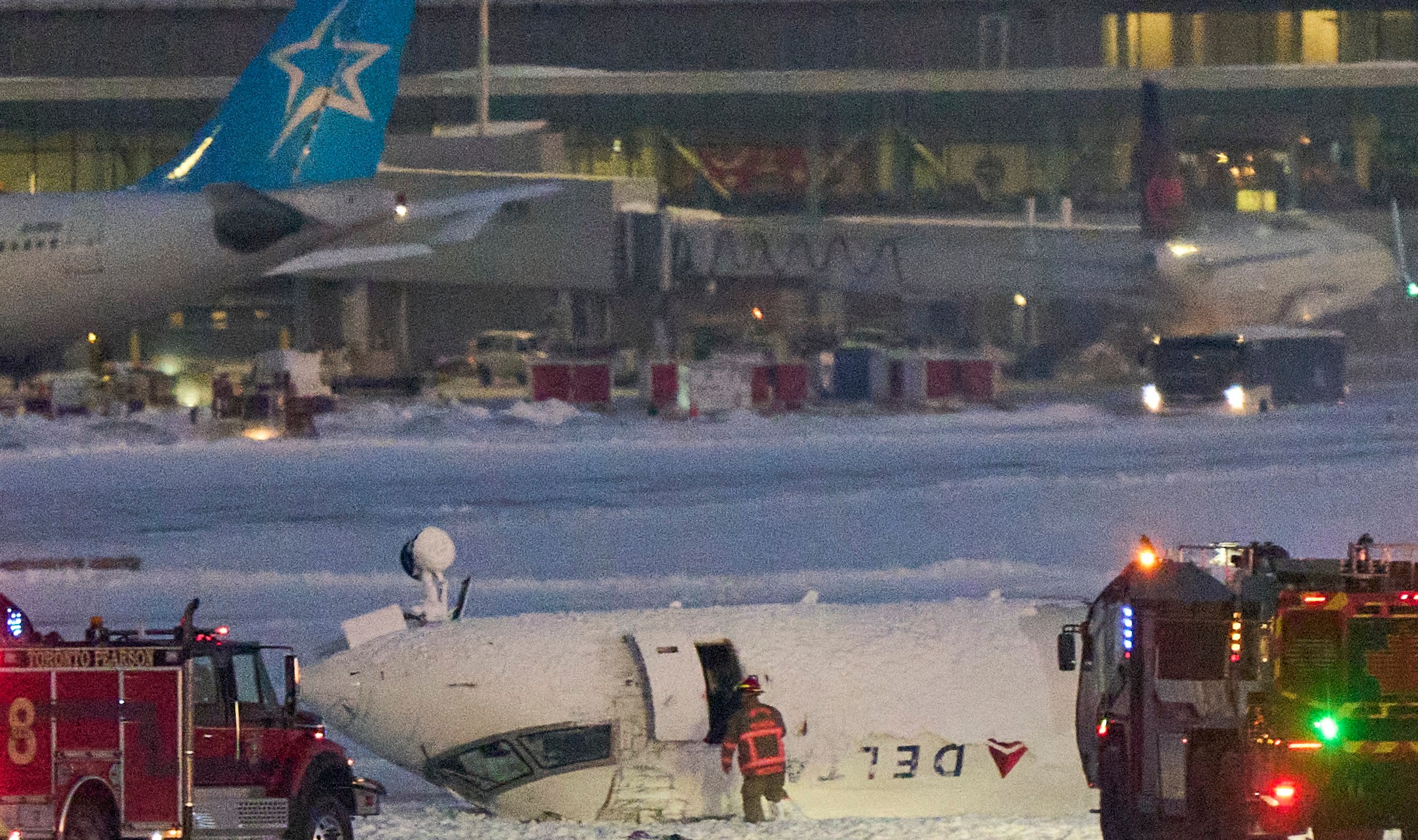 A Delta airlines plane sits on its roof on the tarmac