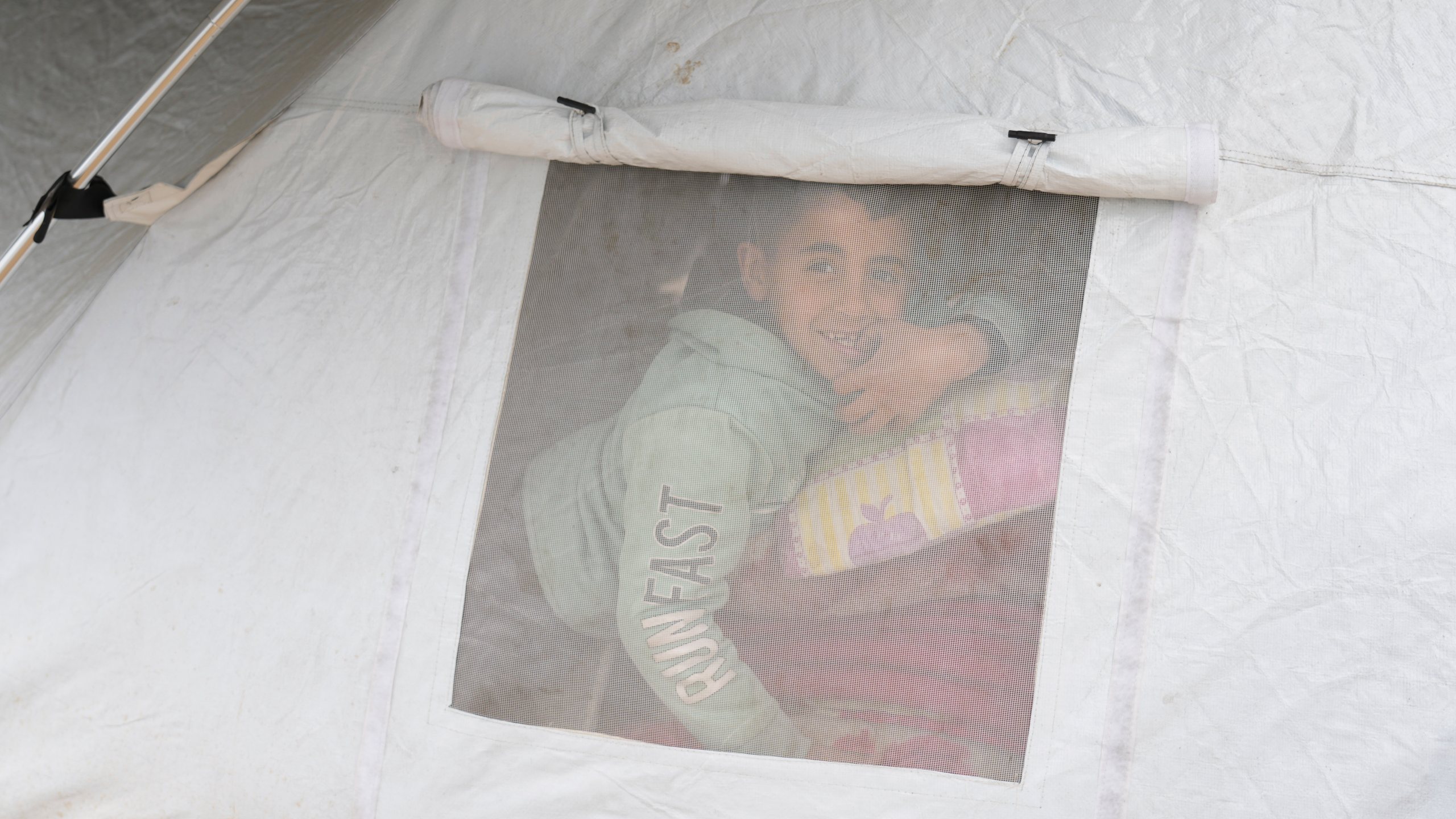 A displaced Palestinian peeks from a tent window in a sprawling camp adjacent to destroyed homes and buildings in Gaza City, Gaza Strip, Saturday, March 1, 2025 during the Muslim holy month of Ramadan. (AP Photo/Abdel Kareem Hana)