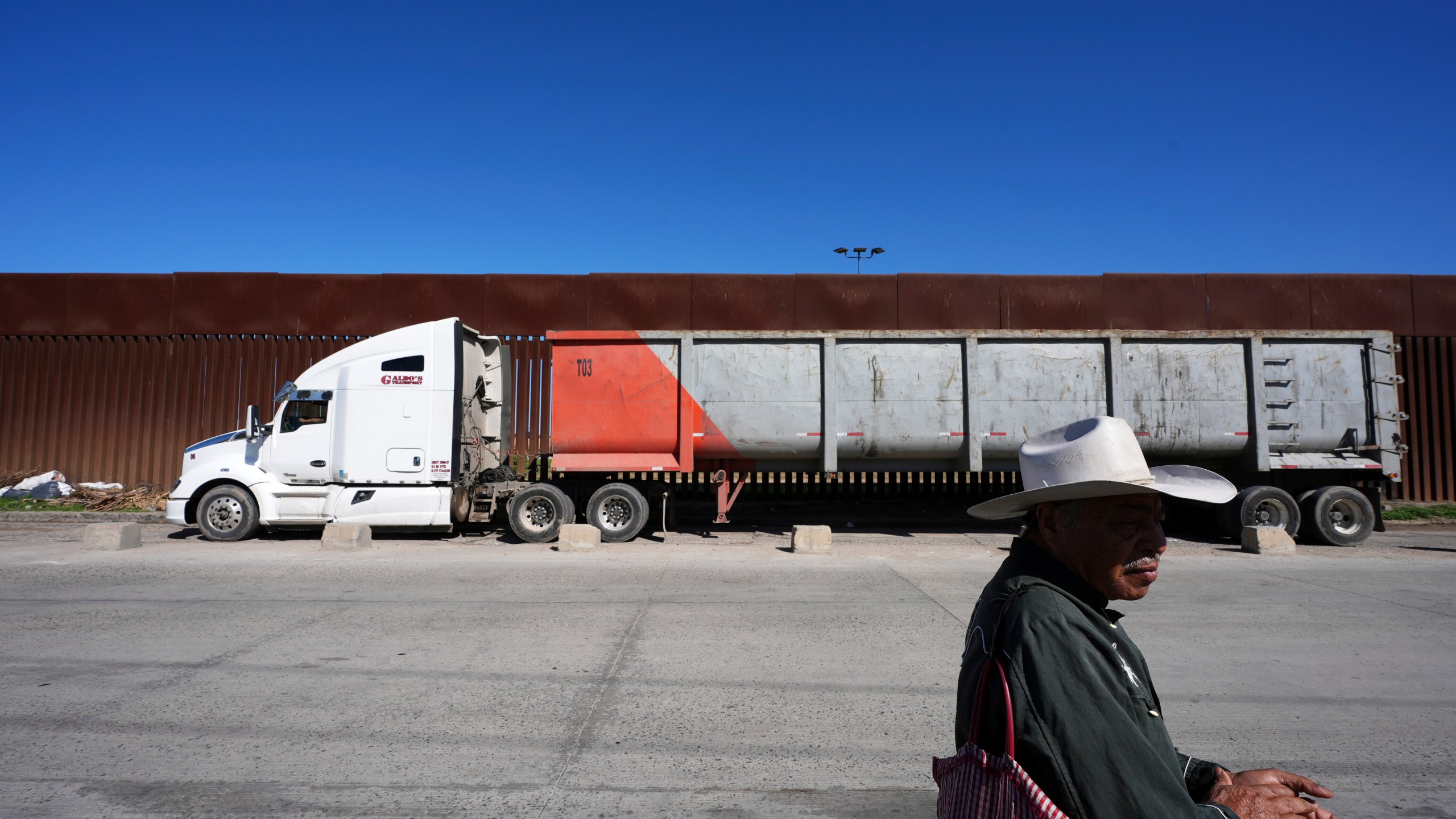 Susano Cordoba, right, sells peanuts to truck drivers lining up to cross the border into the United States as tariffs against Mexico go into effect, Tuesday, March 4, 2025, in Tijuana, Mexico. (AP Photo/Gregory Bull)