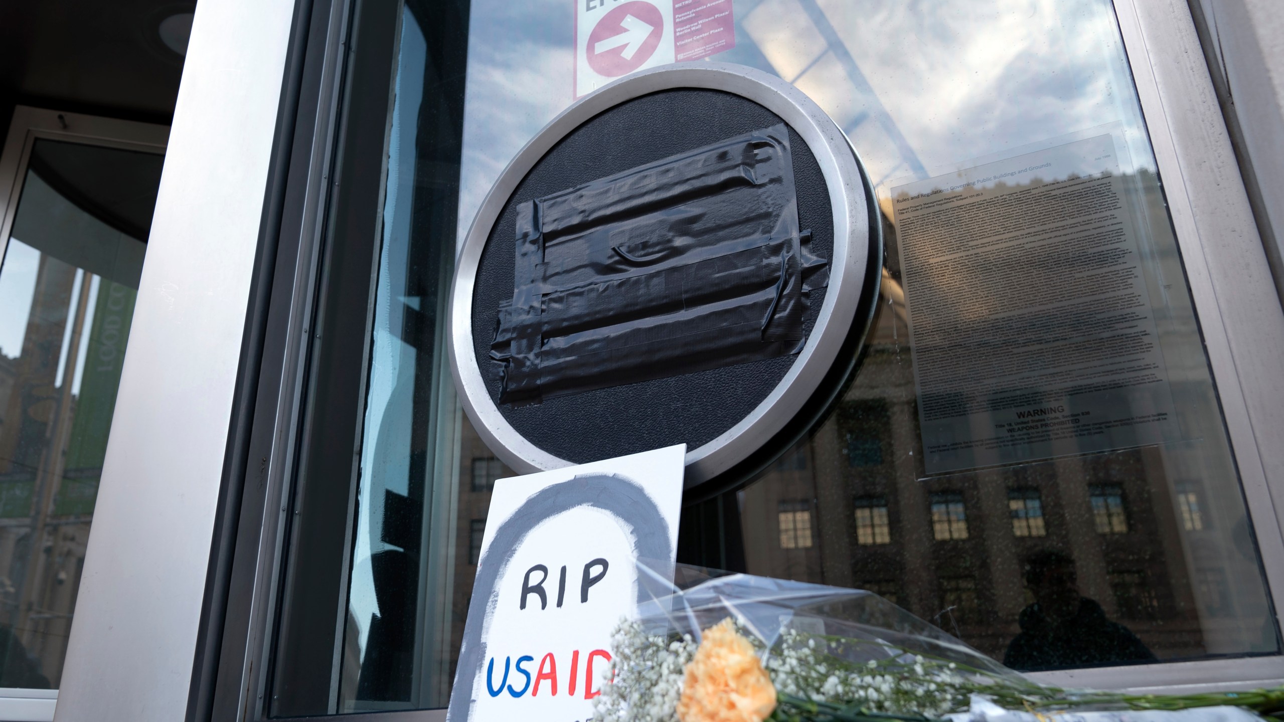 FILE - Flowers and a sign are placed outside the headquarters of the U.S. Agency for International Development, or USAID, Feb. 7, 2025, in Washington. (AP Photo/Jose Luis Magana, file)