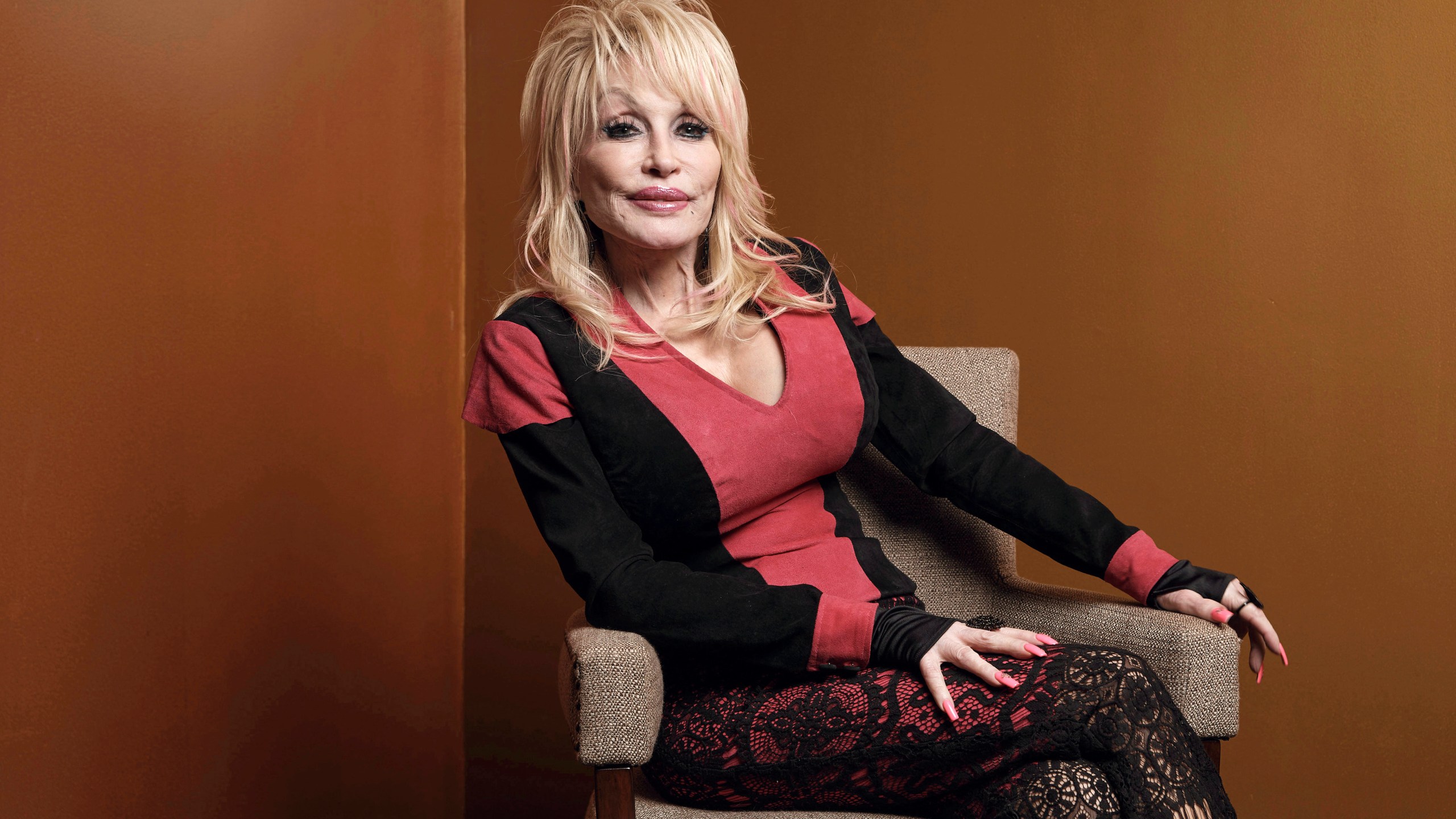Dolly Parton poses on a chair
