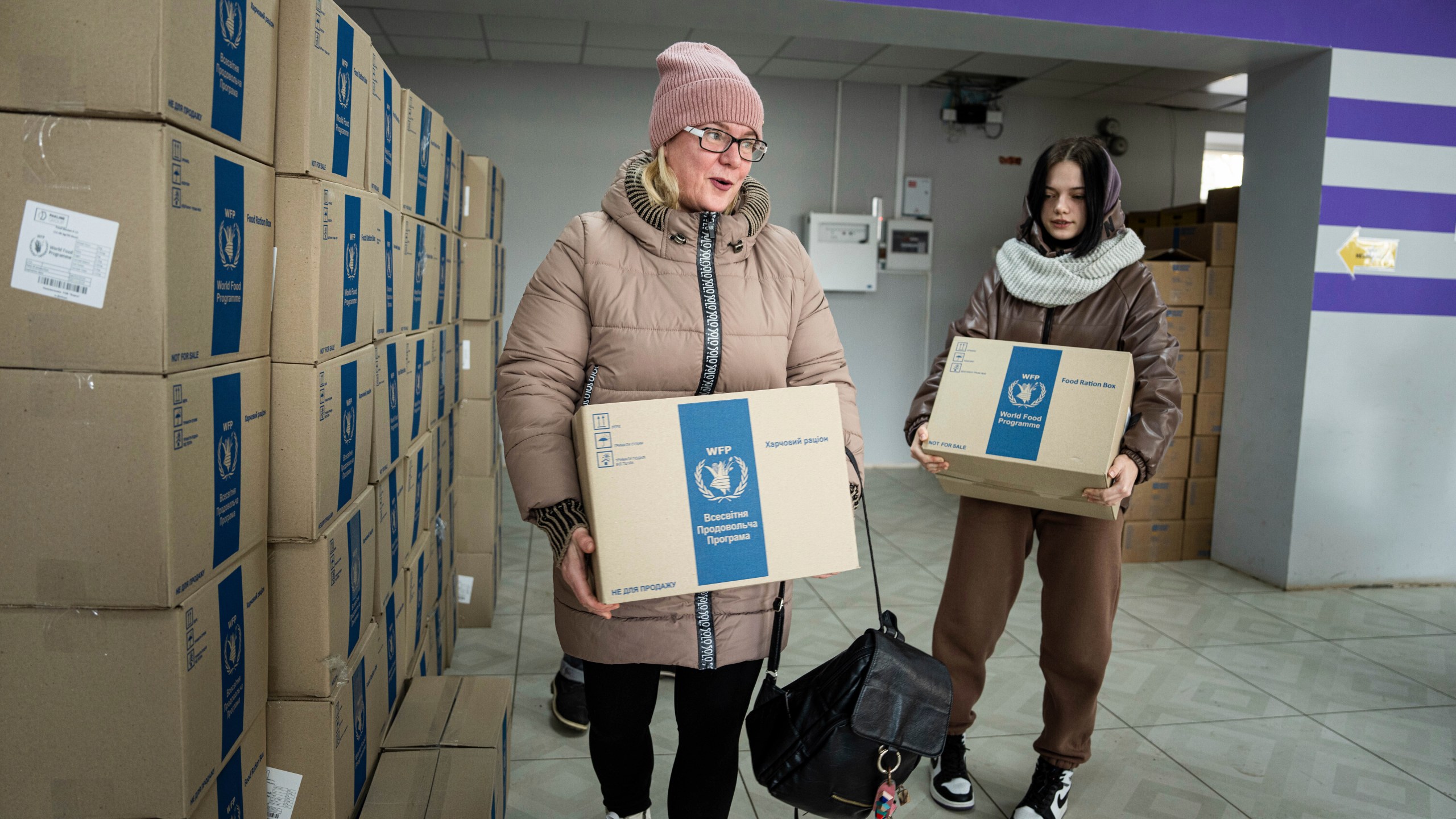 FILE - Tetyana Bobina and her daughter Aleksandra receive humanitarian aid provided by UN World Food Program and ADRA charity organisation for the residents of the region and internally displaced persons at the distribution center in Kostiantynivka, Ukraine, Friday, Feb. 10, 2023. (AP Photo/Evgeniy Maloletka, File)