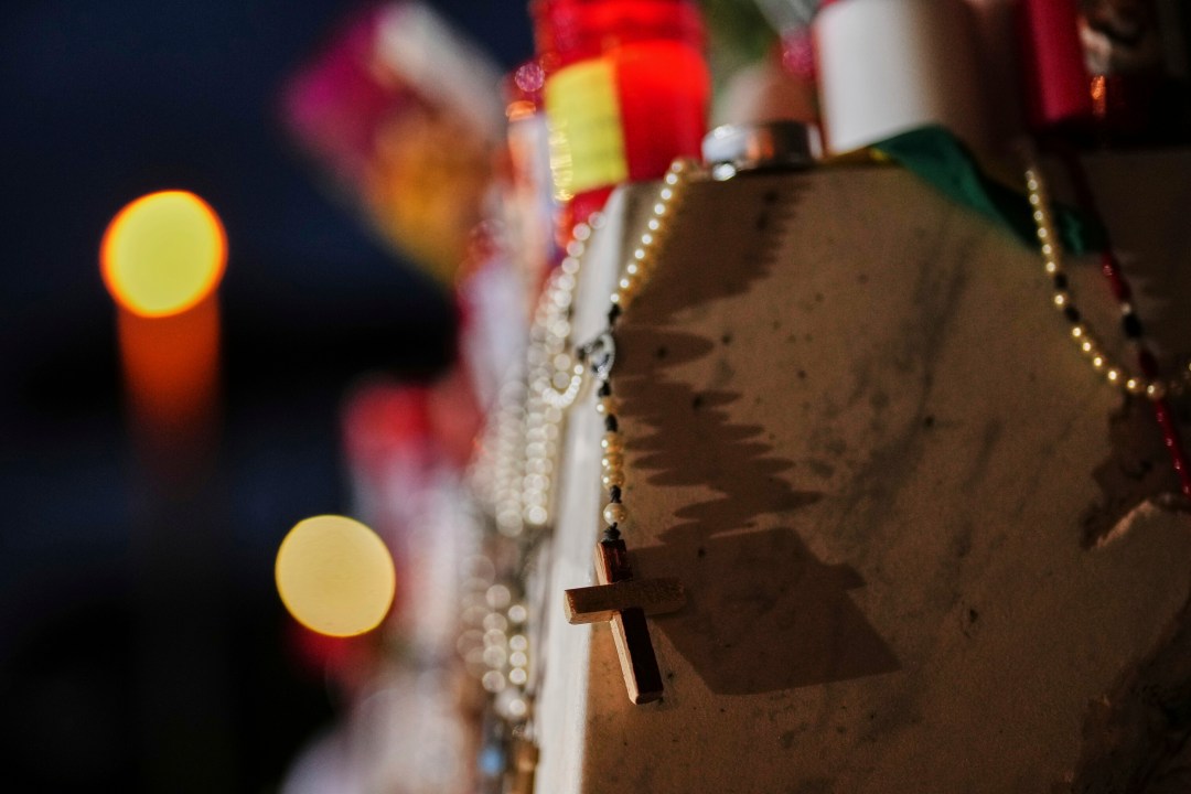 Christian rosaries and light candles are placed at a statue