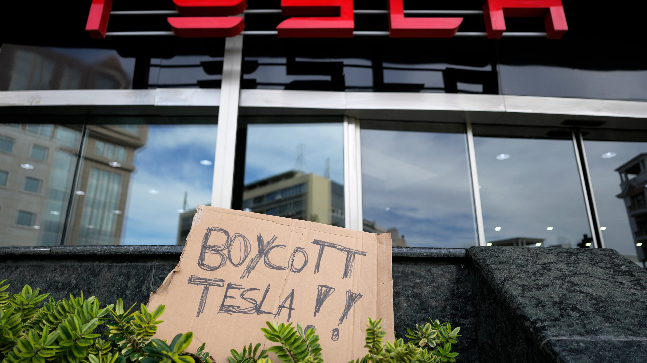 A banner is left outside a Tesla showroom during a demonstration, in Lisbon, Sunday, March 9, 2025. (AP Photo/Armando Franca)