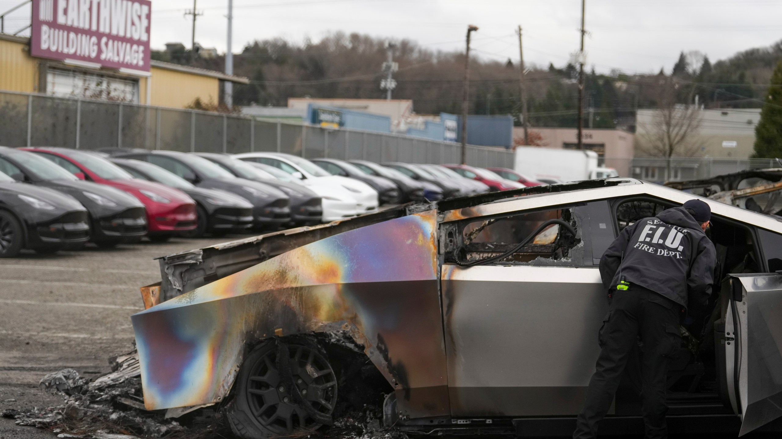 A member of the Seattle Fire Department inspects a burned Tesla Cybertruck at a Tesla lot in Seattle, Monday, March 10, 2025. (AP Photo/Lindsey Wasson)