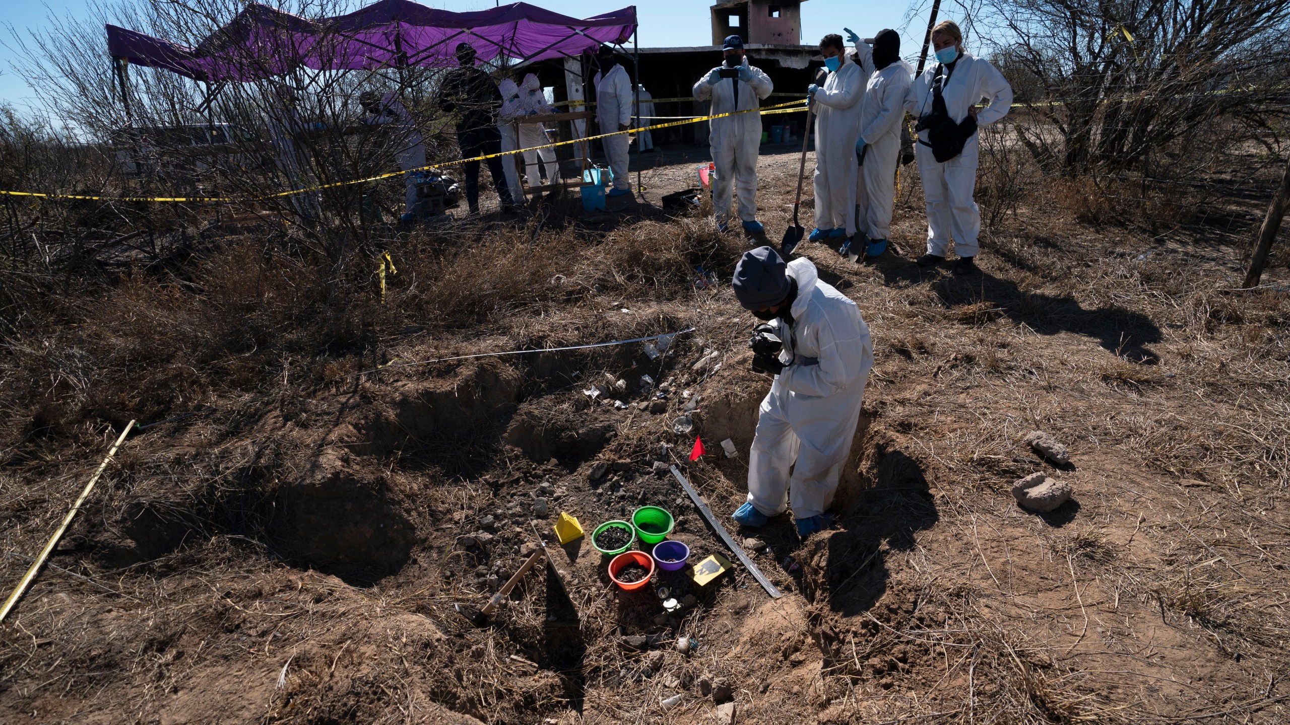 FILE - Forensic technicians excavate a field on a plot of land referred to as a cartel "extermination site" where burned human remains are buried, on the outskirts of Nuevo Laredo, Mexico, Feb. 8, 2022. (AP Photo/Marco Ugarte, File)