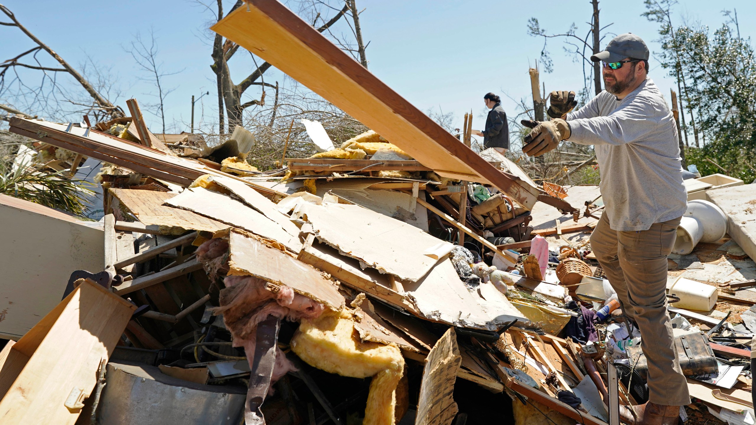 Tommy May, tosses paneling from a tornado destroyed home of relatives, Sunday, March 16, 2025, in Tylertown, Miss. (AP Photo/Rogelio V. Solis)